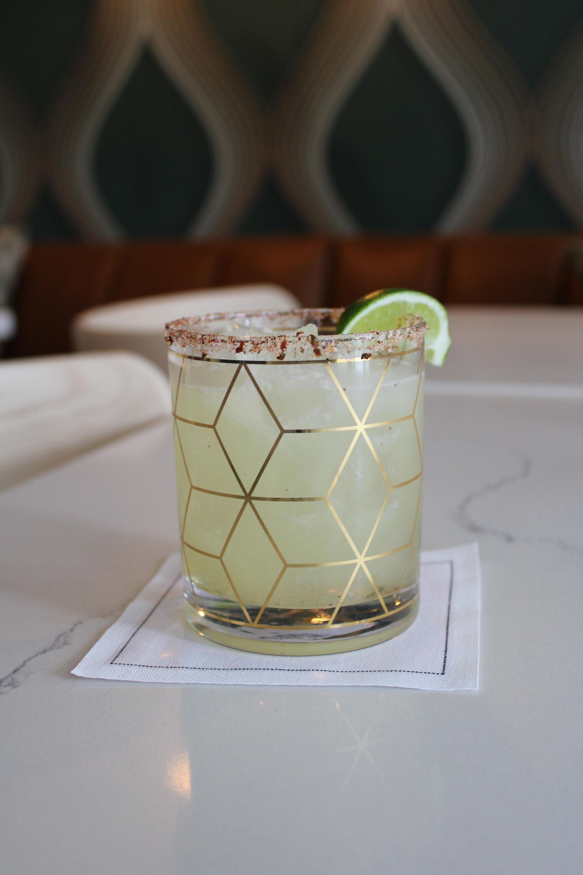 A close up of a margarita in a glass on a napkin on a table.