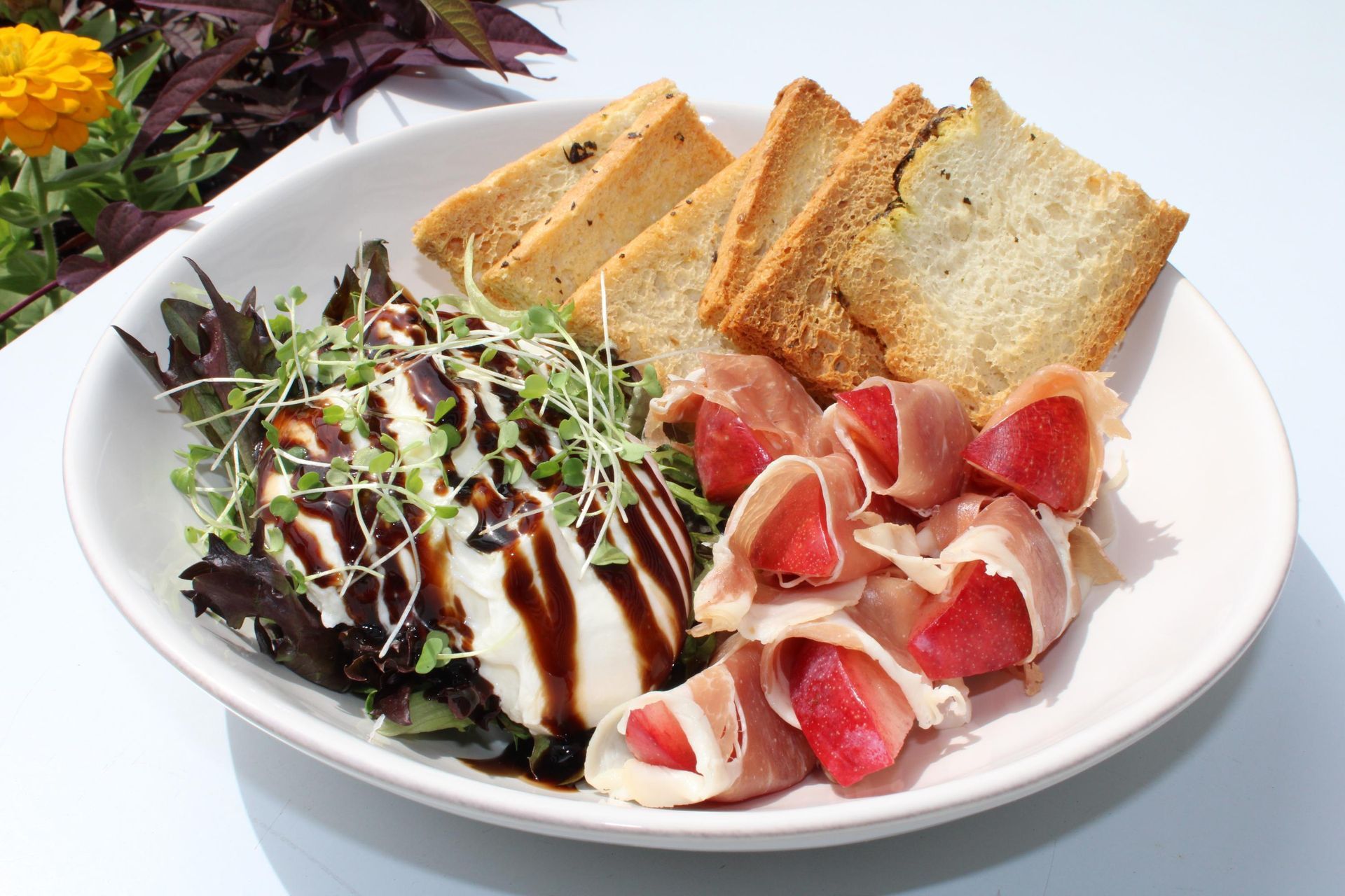 A white plate topped with meat and crackers on a table.