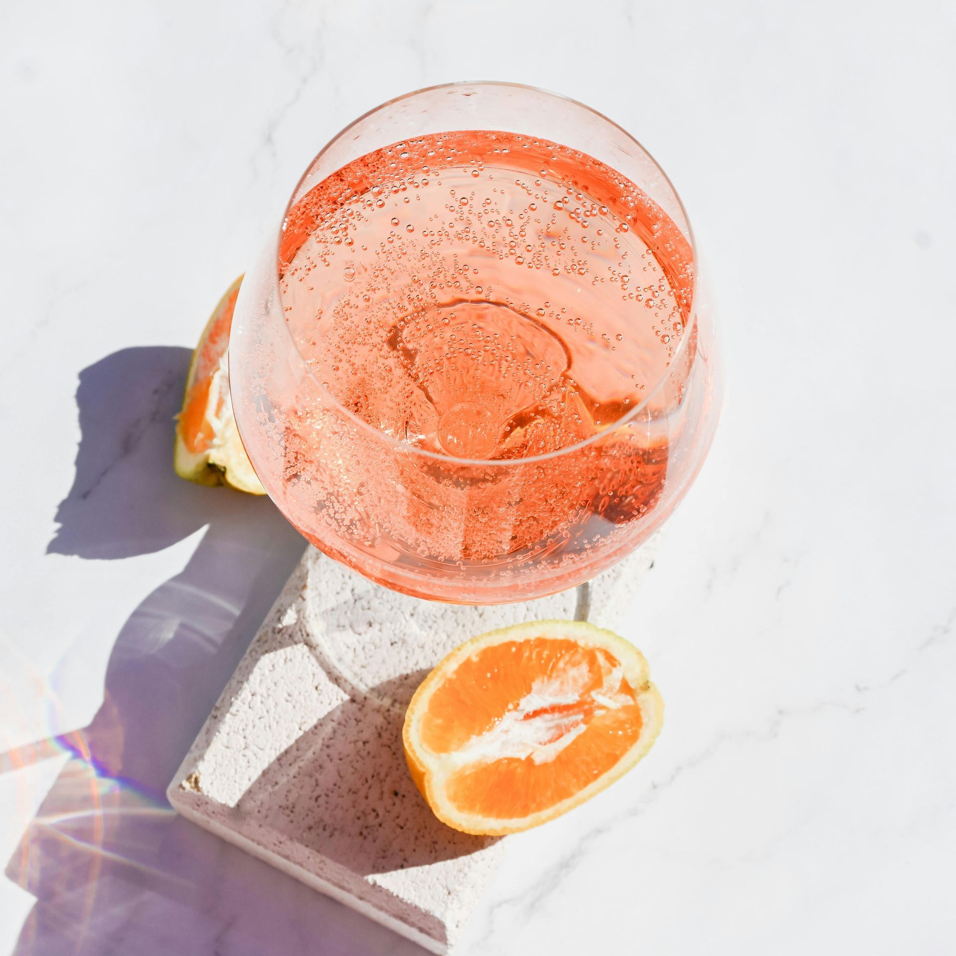 A glass of wine with a slice of orange next to it.