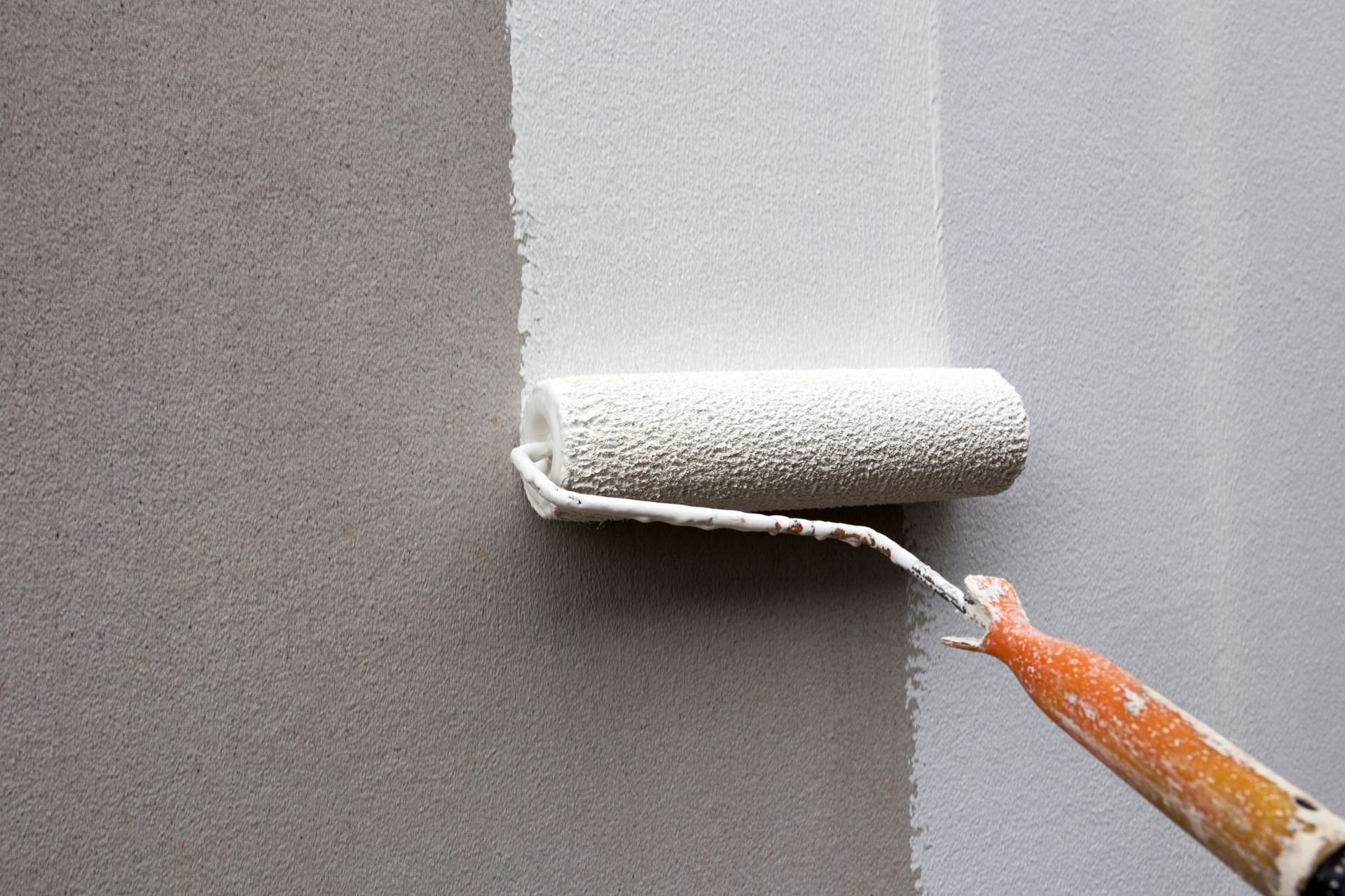 The work of a painter painting with roller to wall.