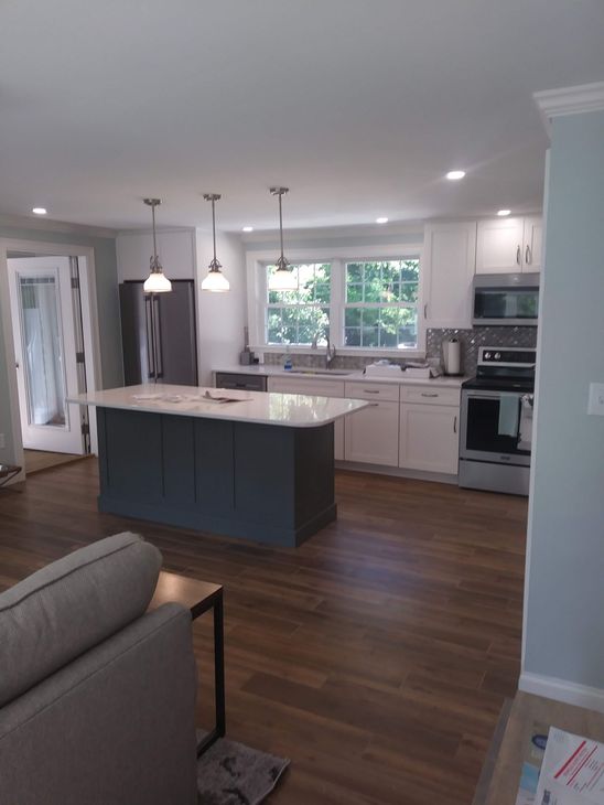 Newly renovated kitchen with gray island, white cabinets, stainless steel appliances, and wood floors.