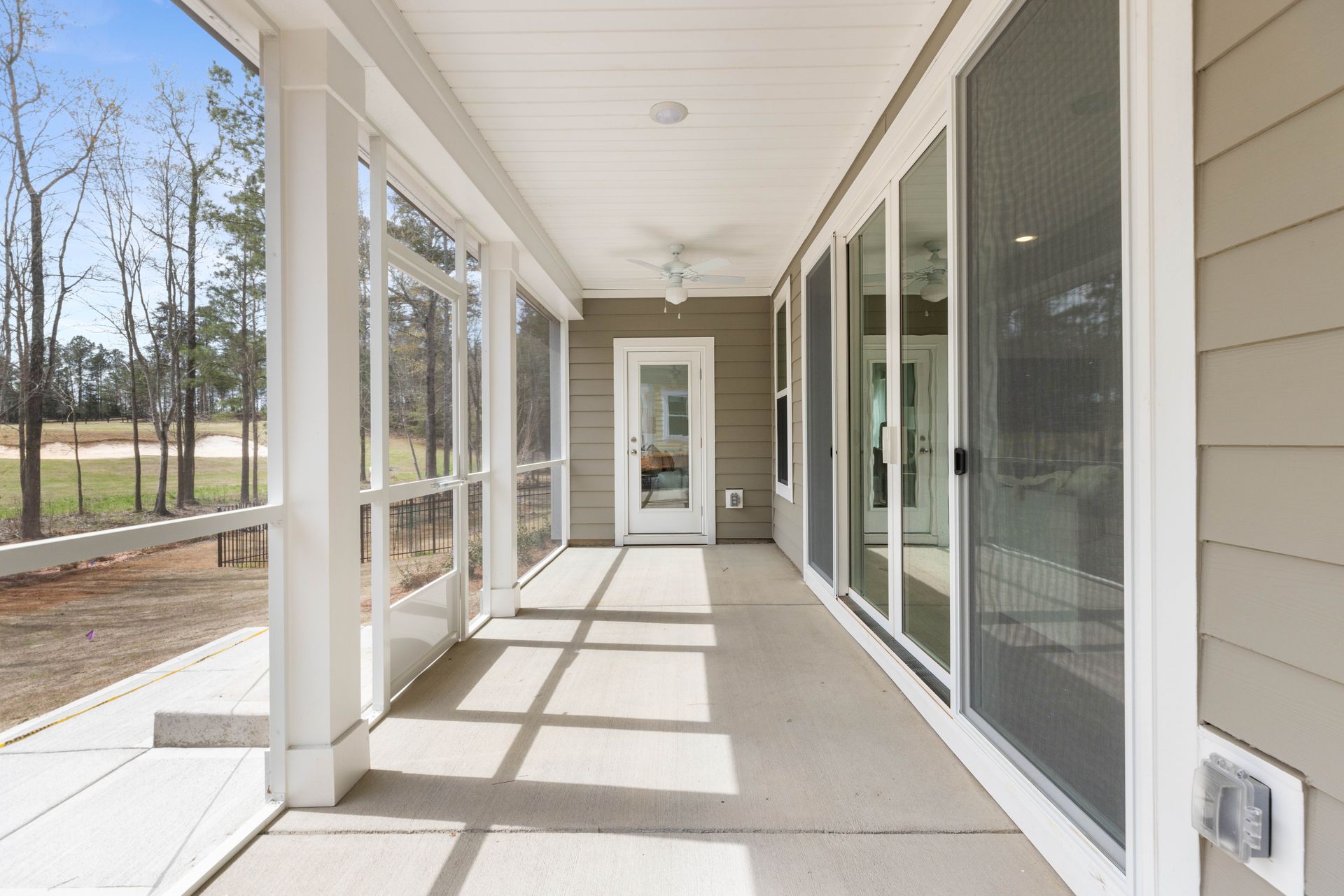 A screened in porch with sliding glass doors and a ceiling fan.