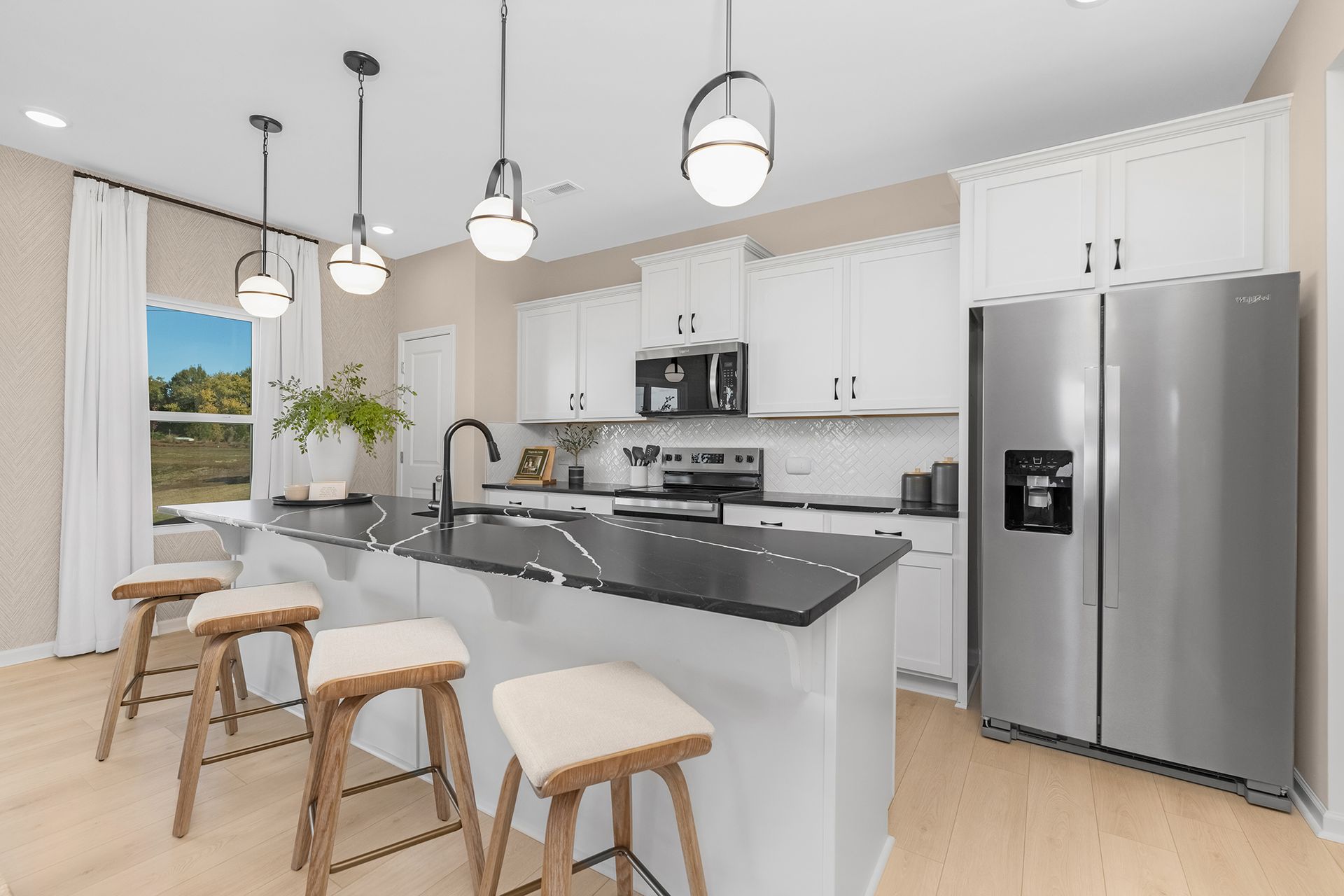 Modern white kitchen with island, stainless steel appliances, and three gray stools.