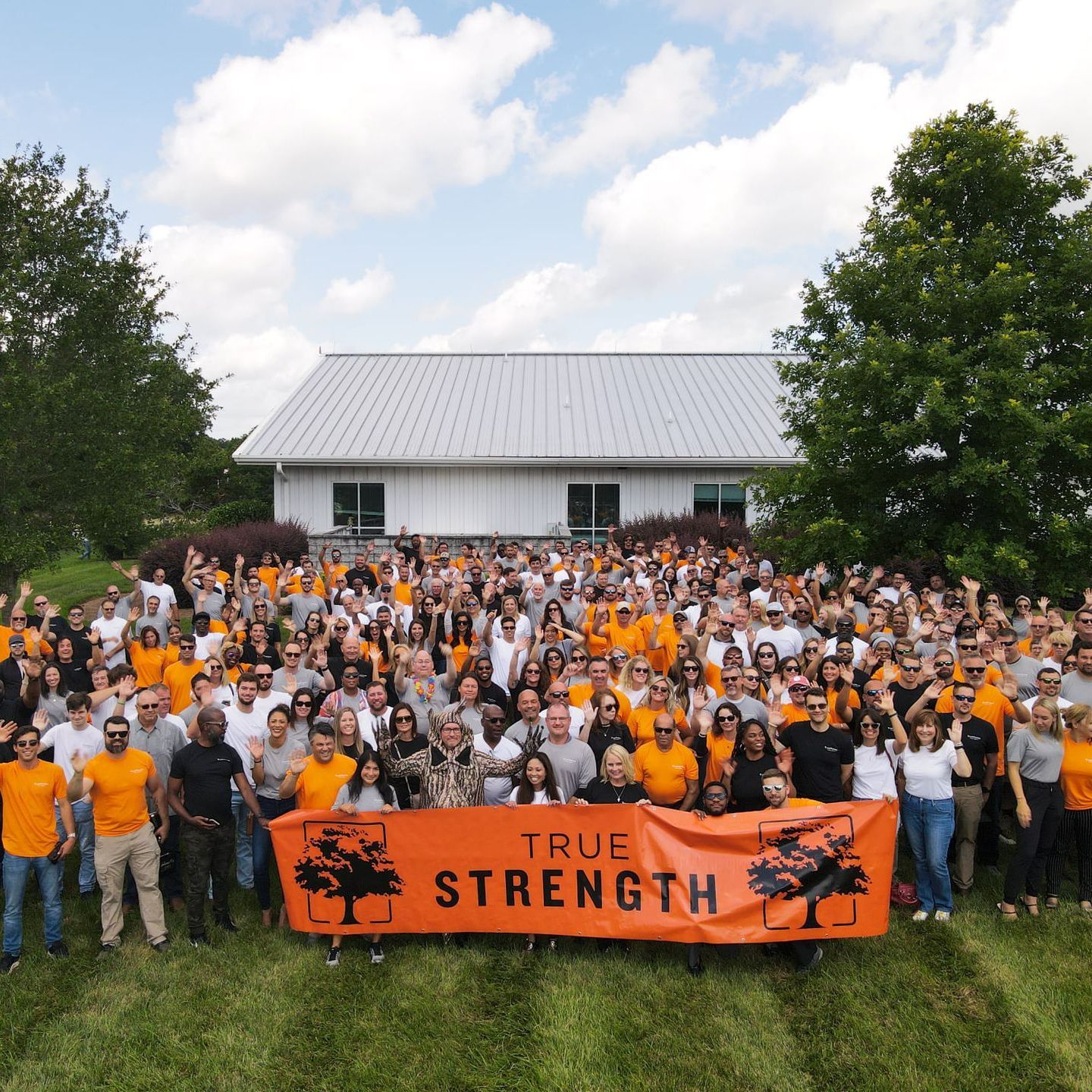 a large group of people holding an orange banner that says true strength
