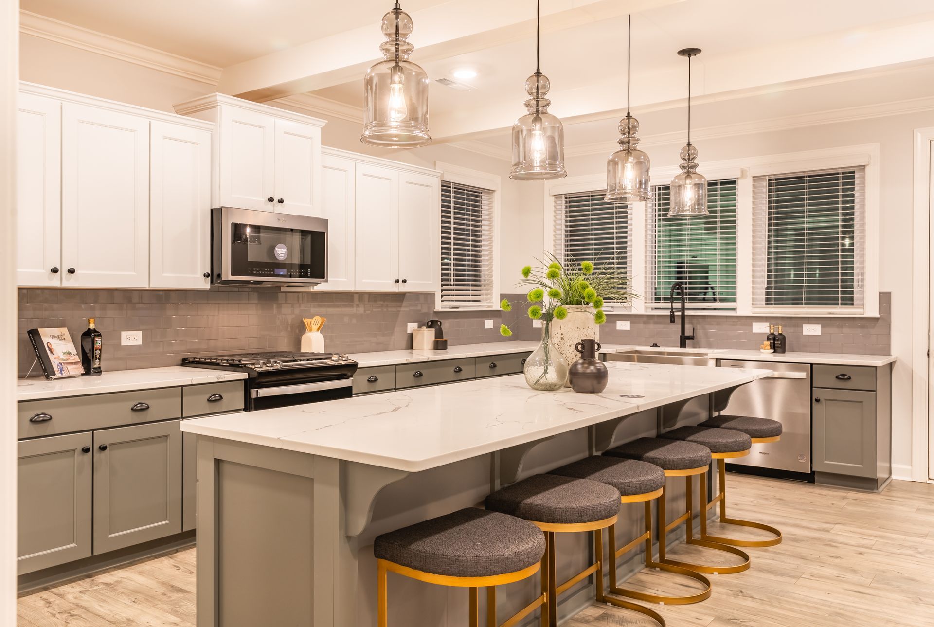a kitchen with gray cabinets , white cabinets , stainless steel appliances , a large island and stools .