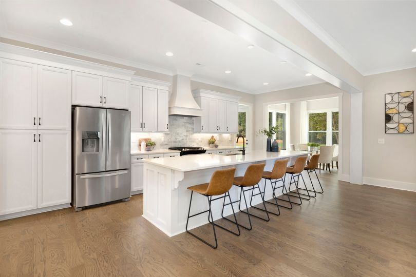 A kitchen with white cabinets , stainless steel appliances , and a large island.