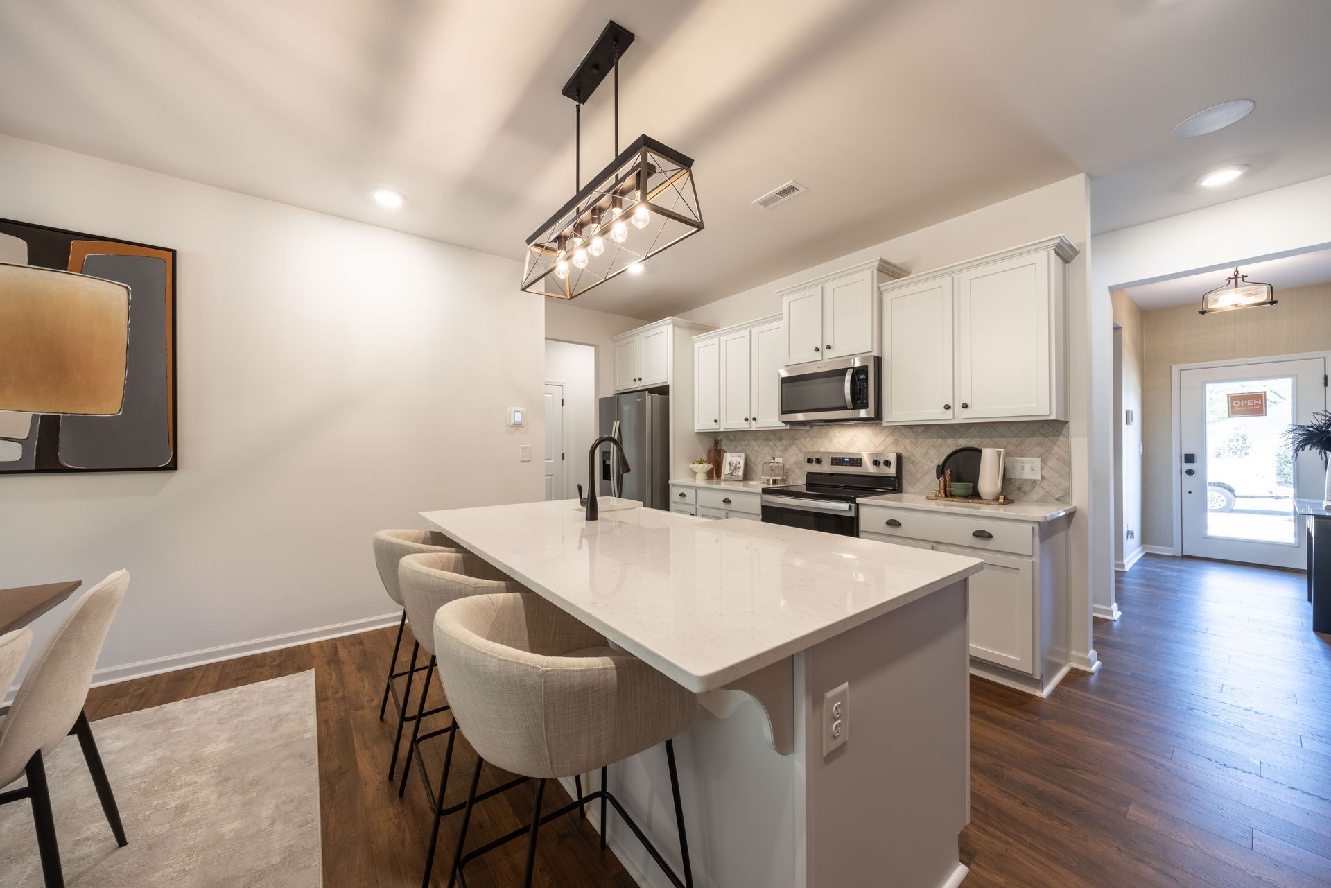 A kitchen with white cabinets , stainless steel appliances , and a large island - Abigale Floorplan by True Homes.