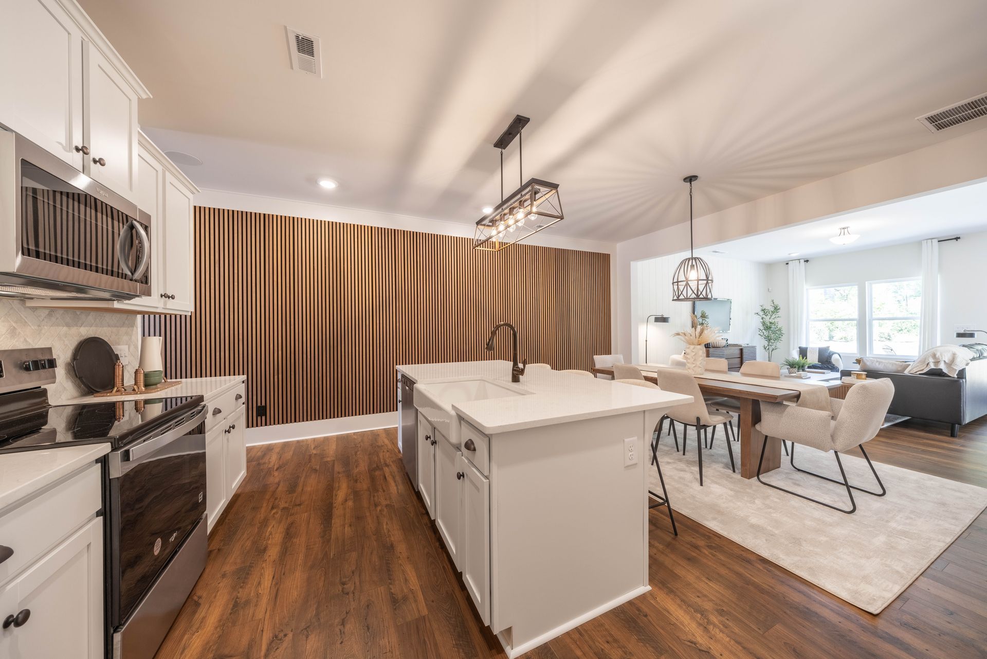 A kitchen with white cabinets and stainless steel appliances and a large island - Abigale Floorplan by True Homes.