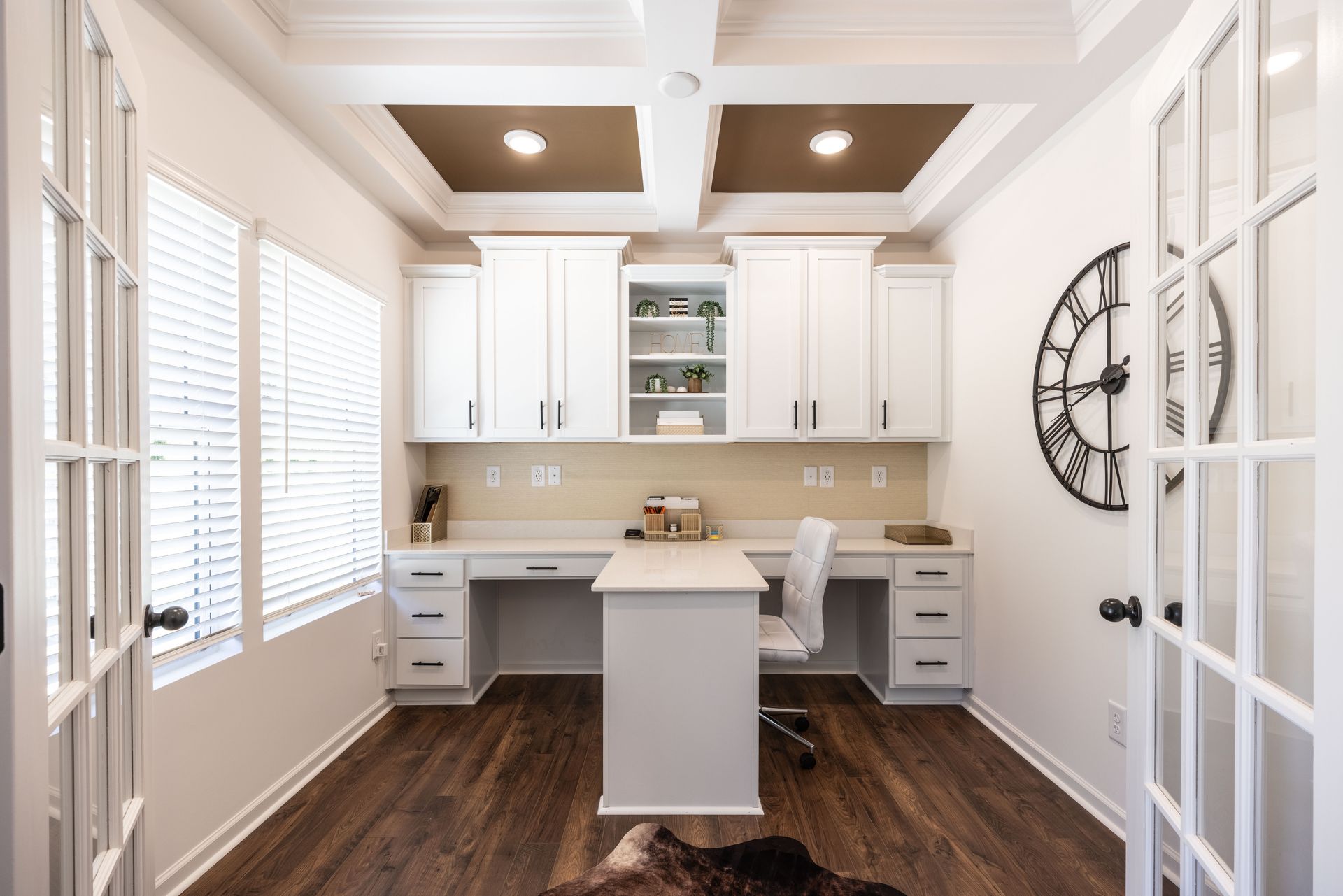A home office with two desks and a clock on the wall - Abigale Floorplan by True Homes.