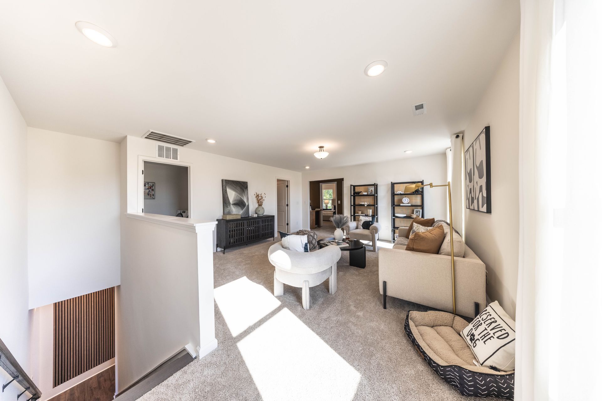 A living room with a couch , chairs , and a dog bed - Abigale Floorplan by True Homes.