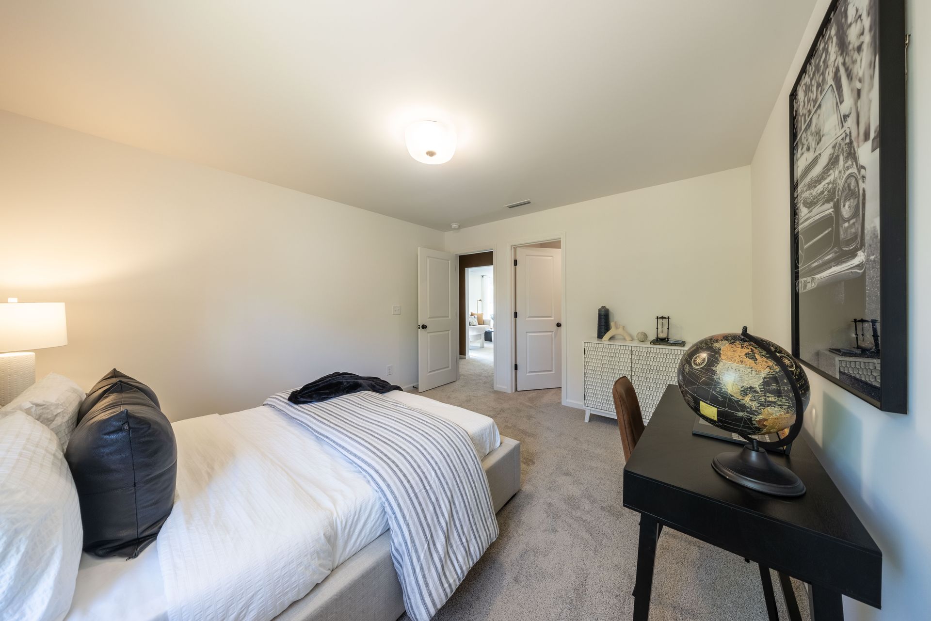 A bedroom with a bed and a desk with a globe on it - Abigale Floorplan by True Homes.