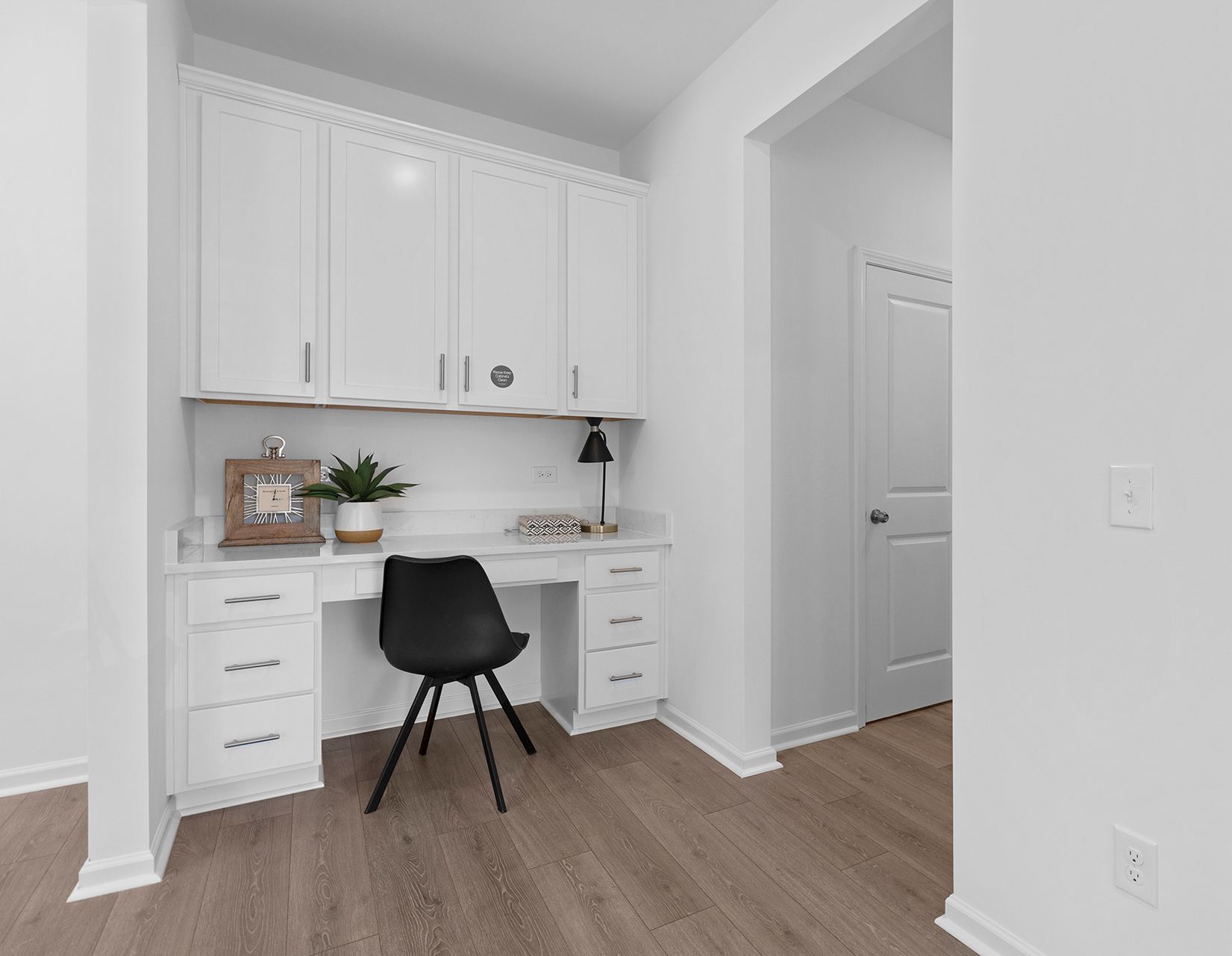 There is a desk with a black chair in the middle of the room.