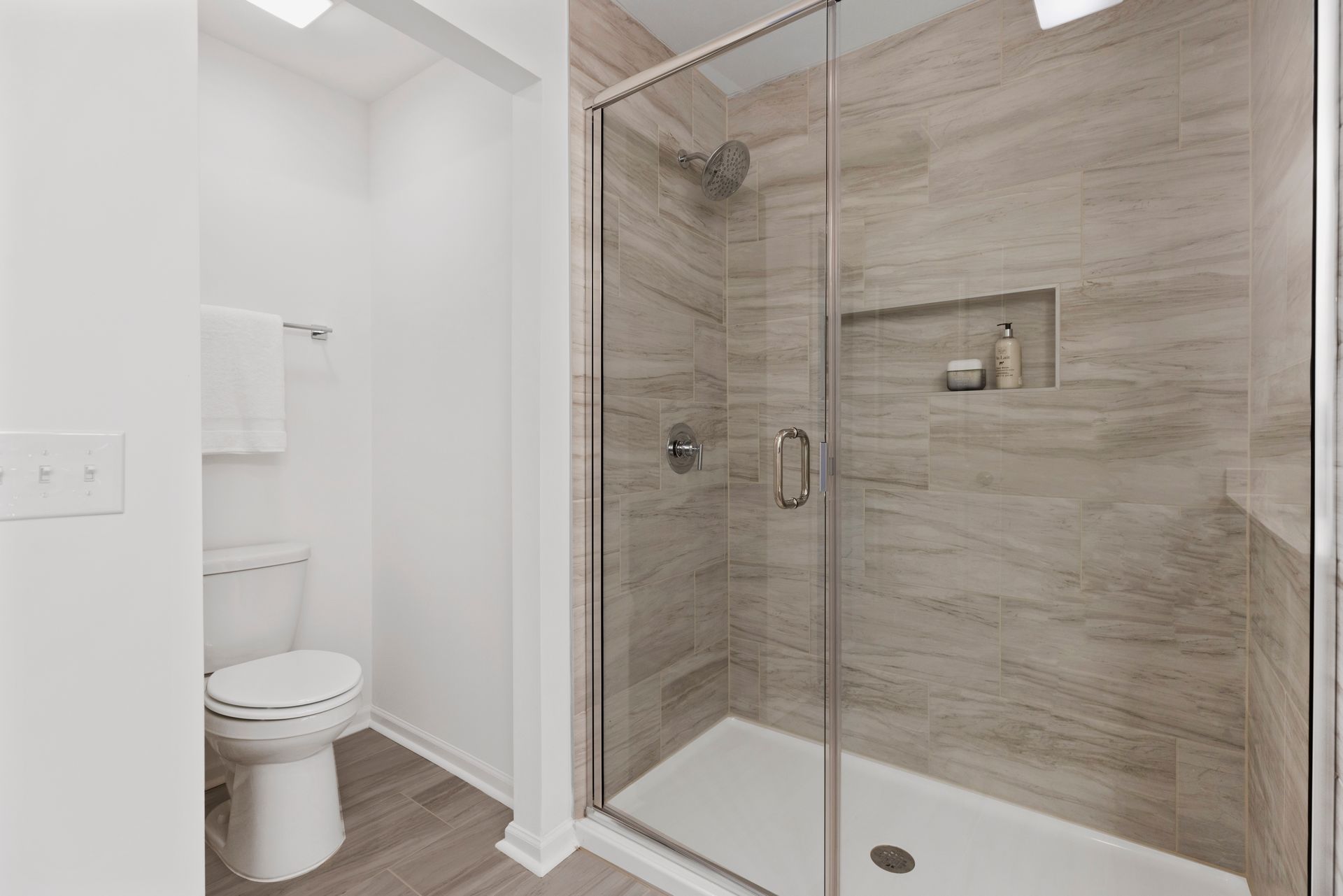 A bathroom with a toilet and a walk in shower with a glass door.