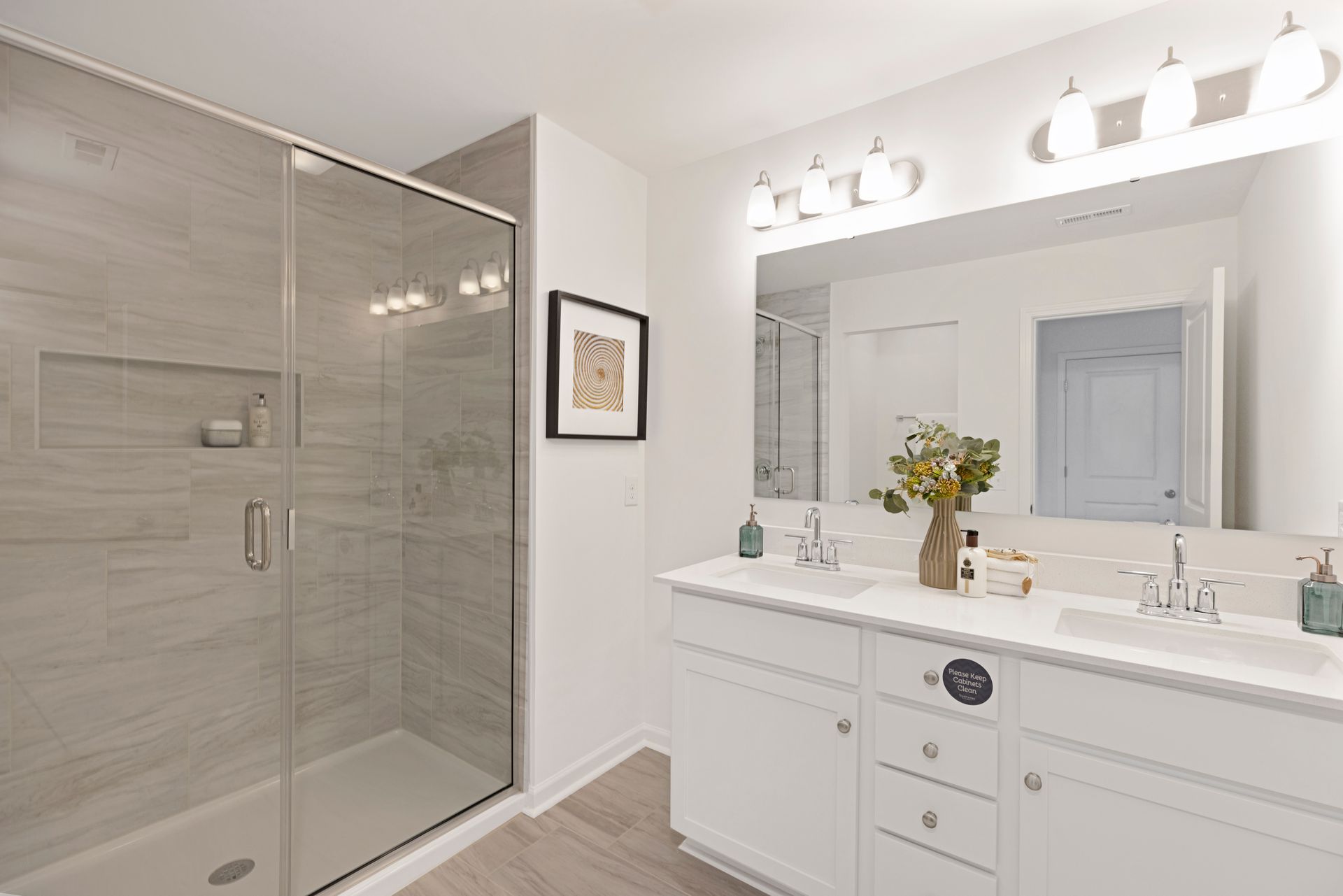 A bathroom with two sinks , a walk in shower and a large mirror.
