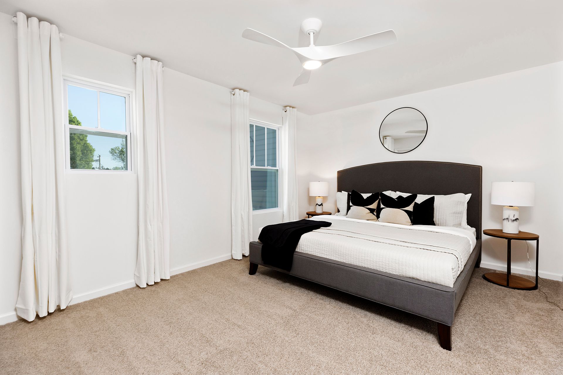 A bedroom with a large bed , a ceiling fan , and a window.