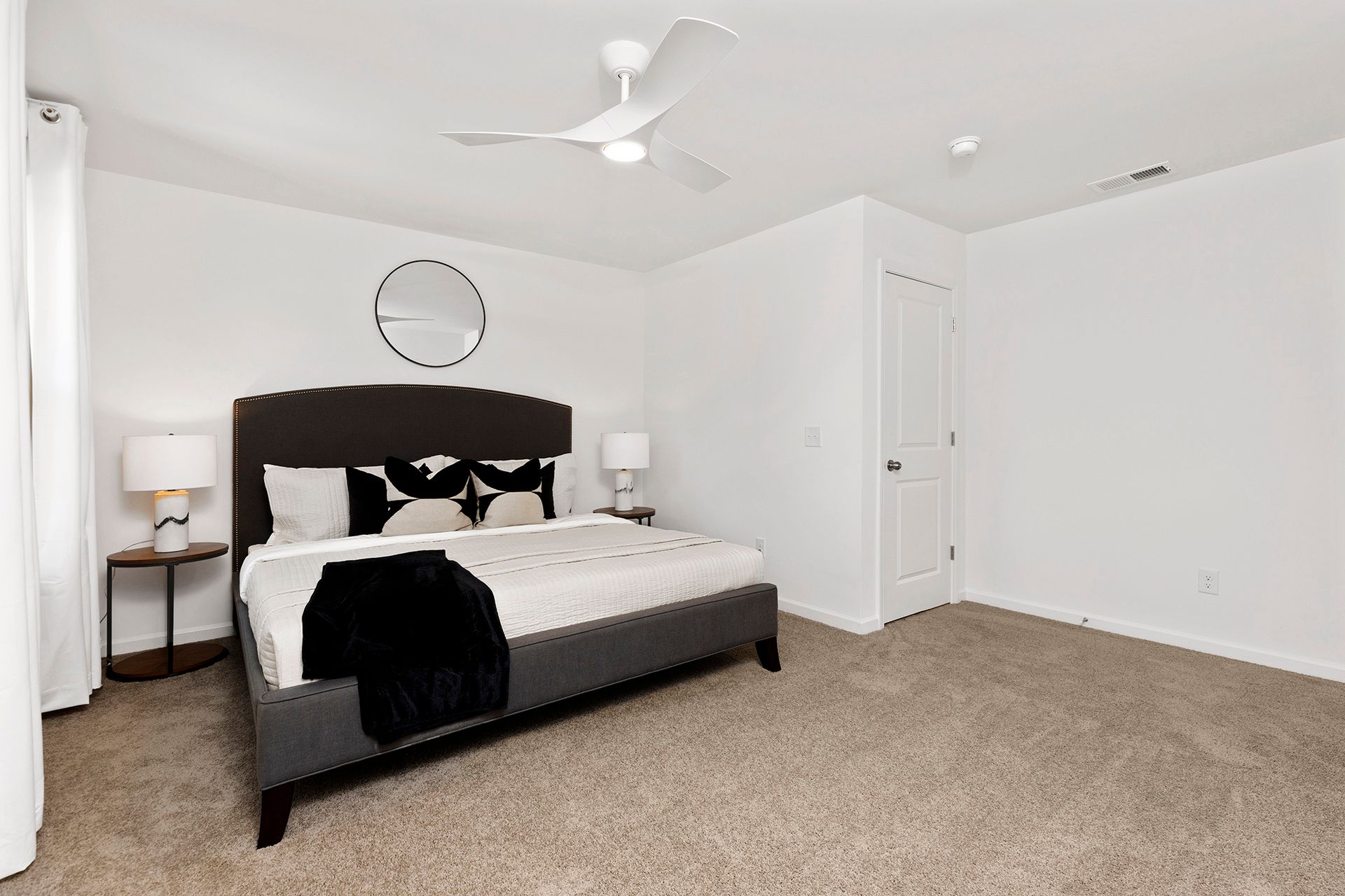 A bedroom with a king size bed and a ceiling fan.