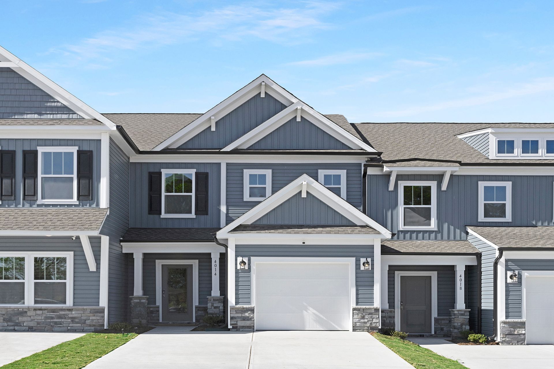 A large gray house with a white garage and a driveway.