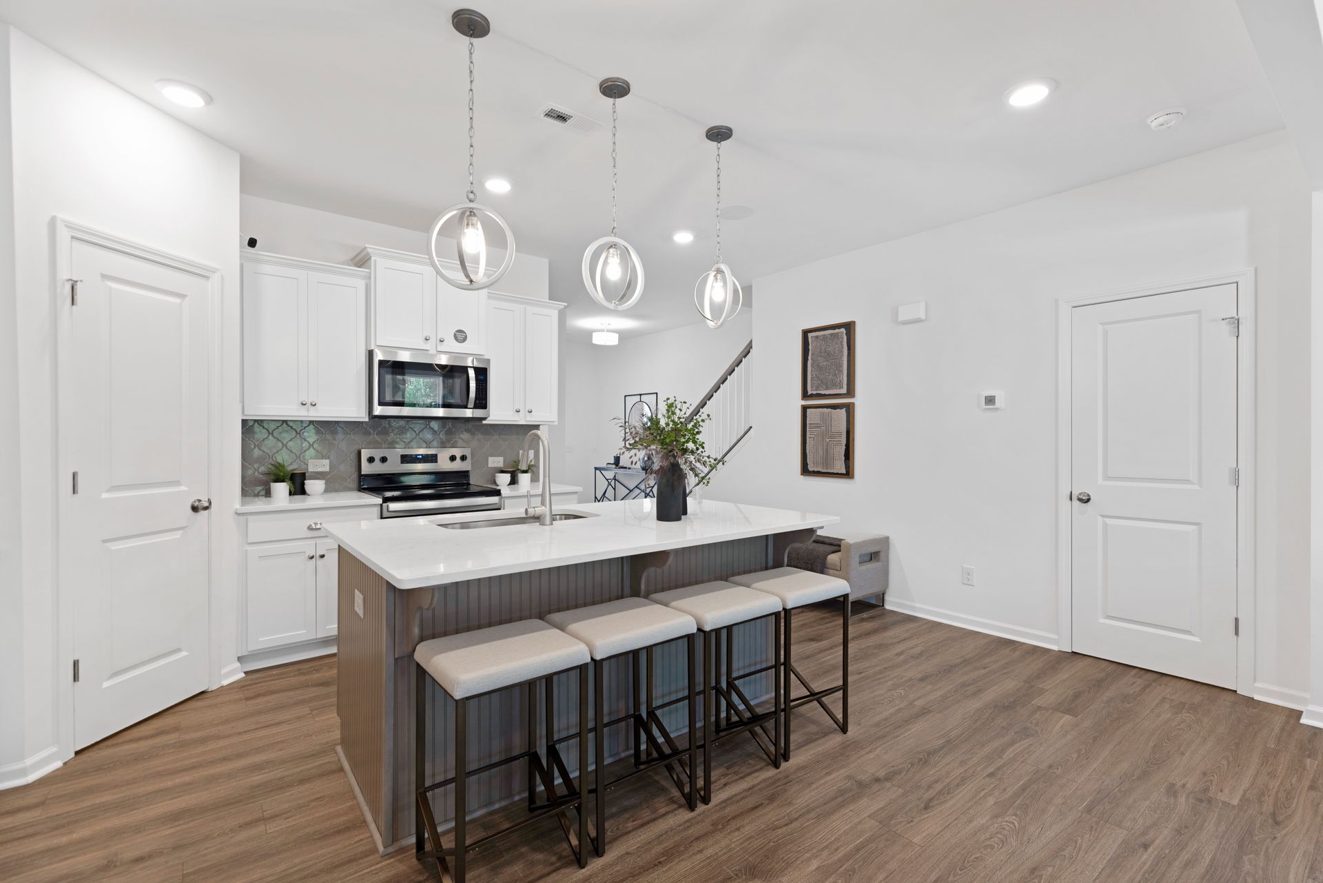 A kitchen with white cabinets , stainless steel appliances , and a large island.