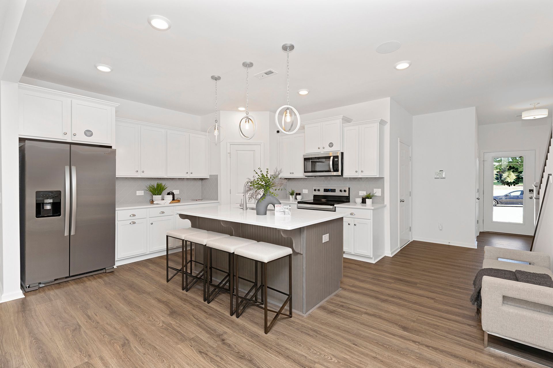 A kitchen with white cabinets , stainless steel appliances , and a large island.