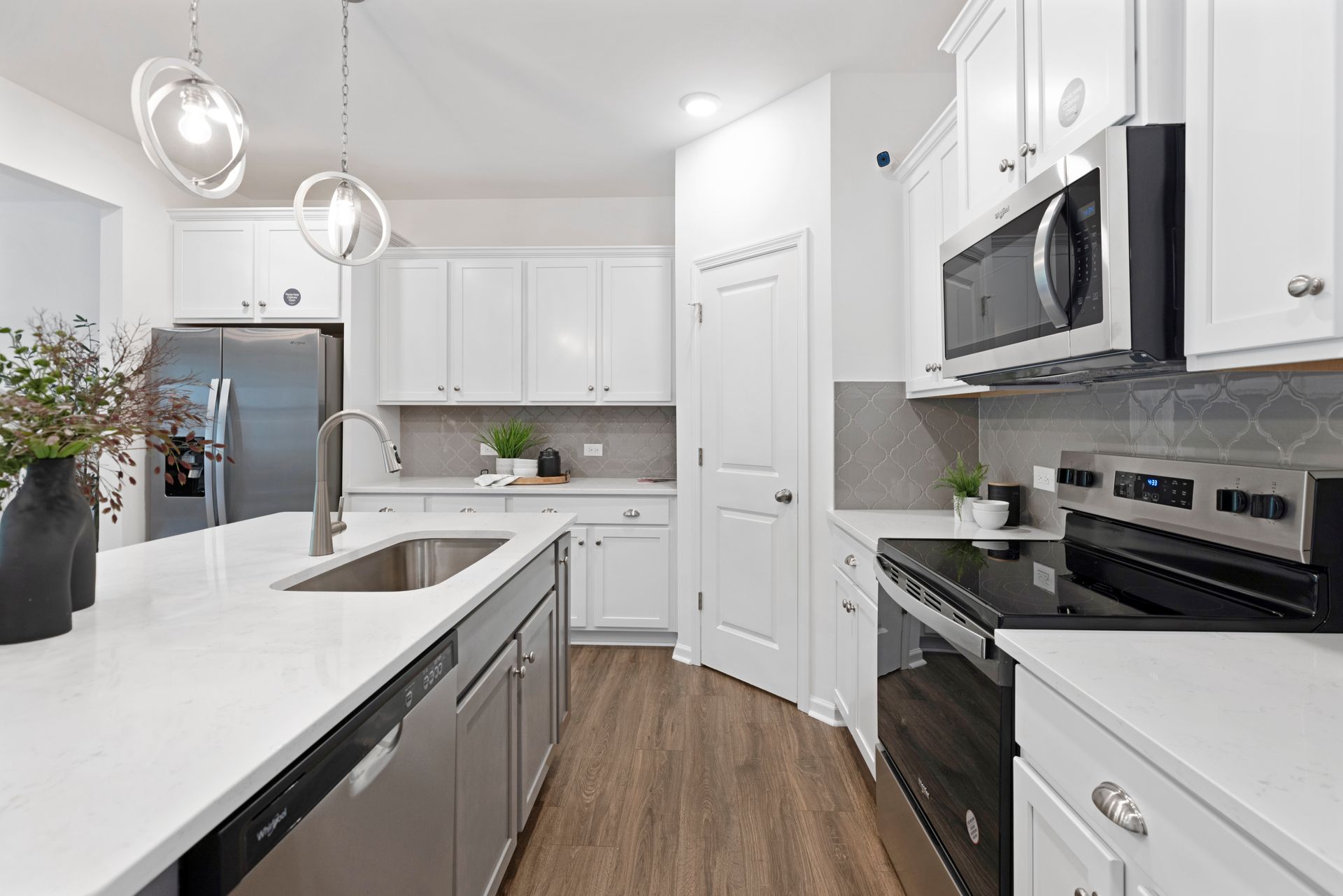 A kitchen with white cabinets , stainless steel appliances , a sink , and a refrigerator.