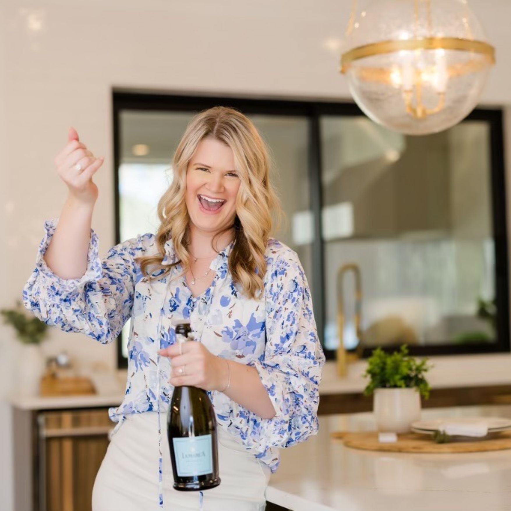 A woman is holding a bottle of champagne in a kitchen