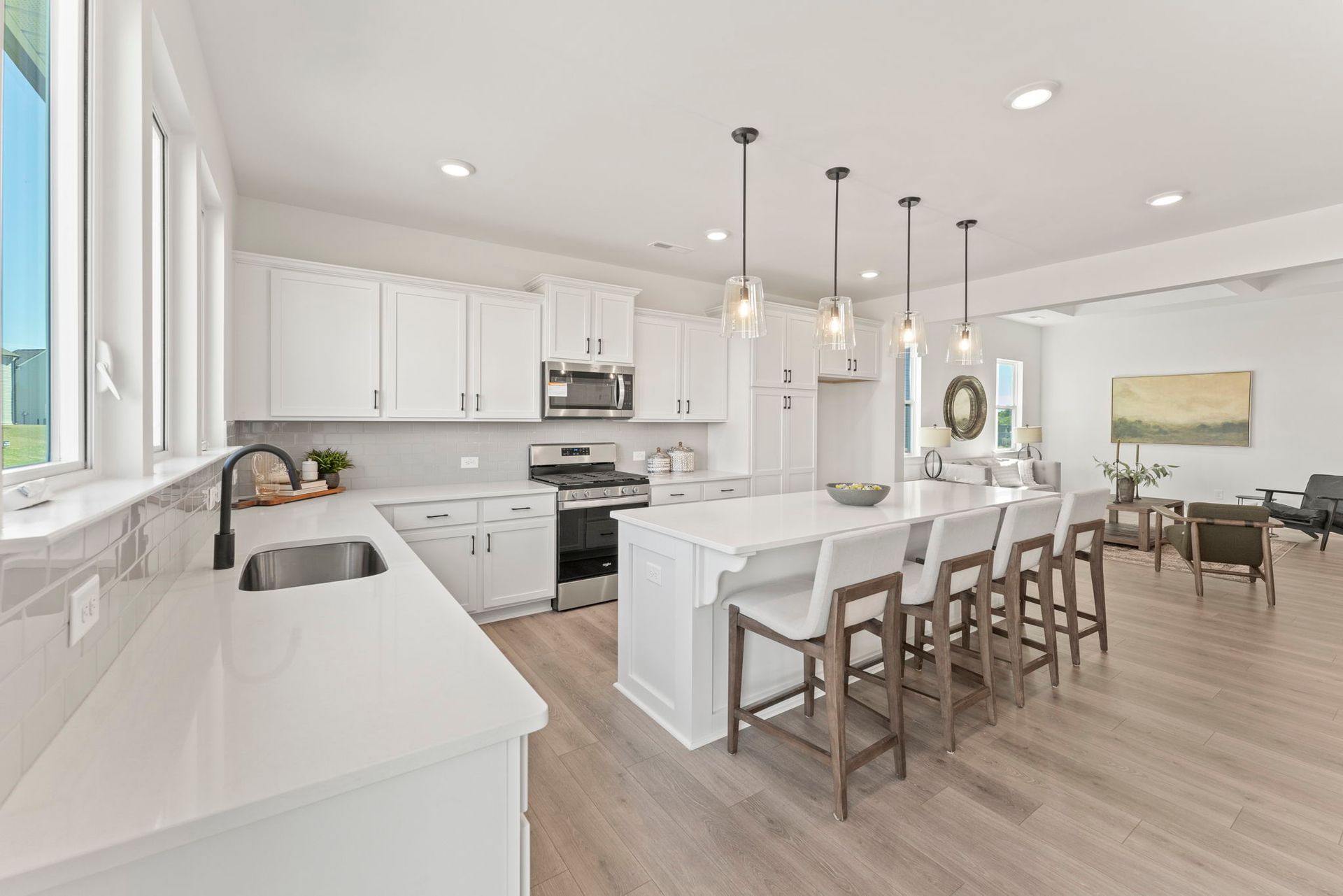 A kitchen with white cabinets , a large island , and stools.