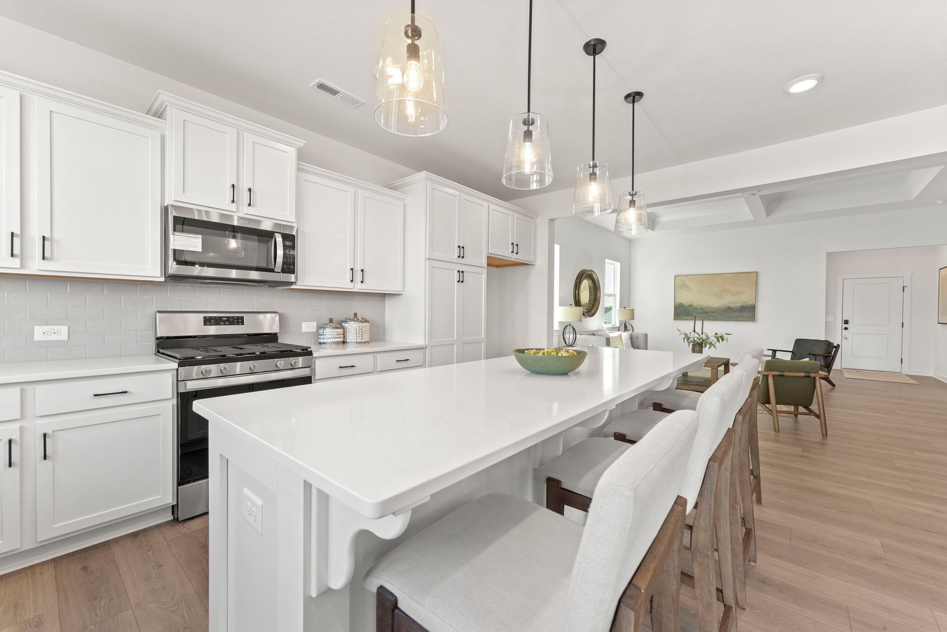 A kitchen with white cabinets , stainless steel appliances , and a large island.