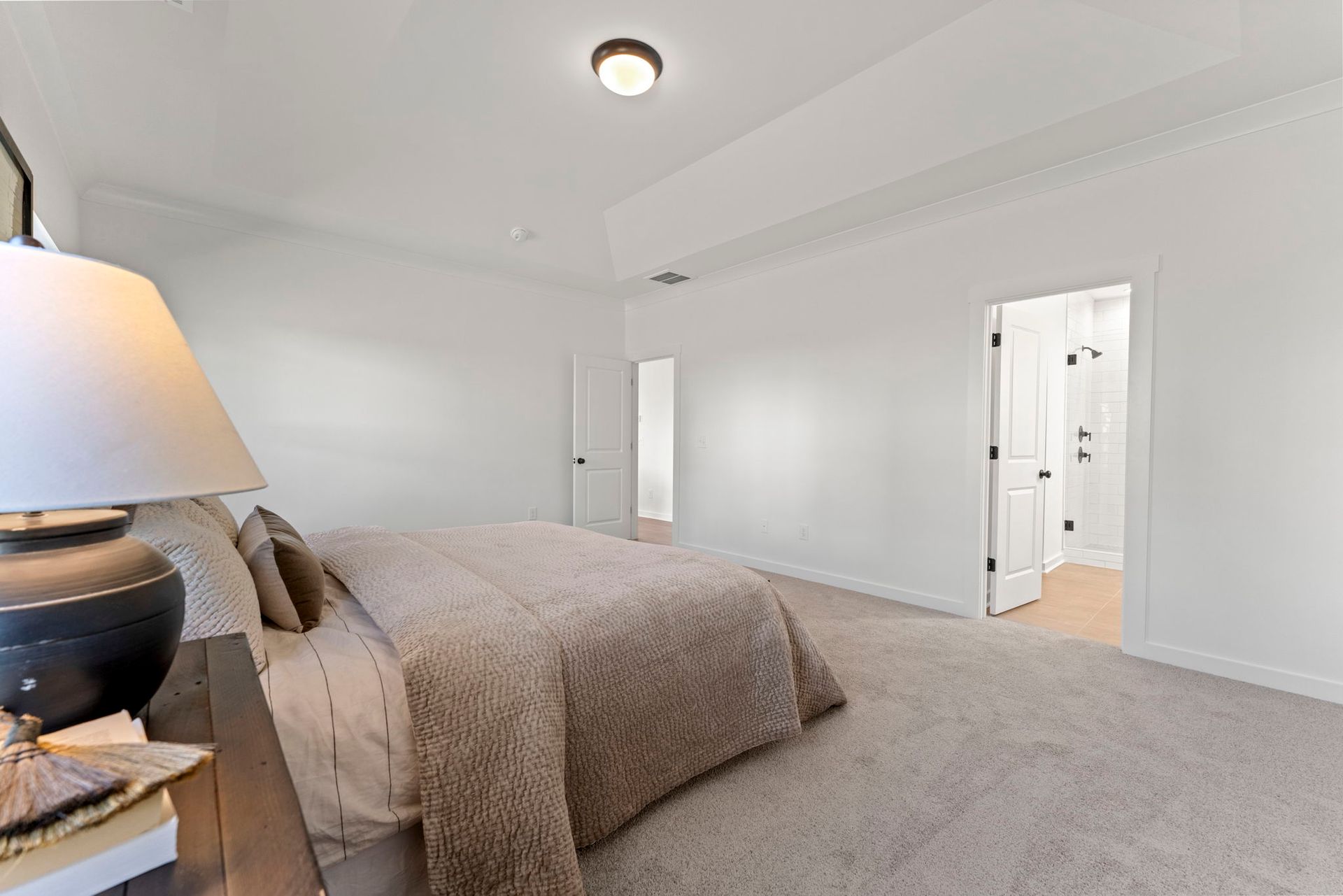 A bedroom with a large bed and a lamp.