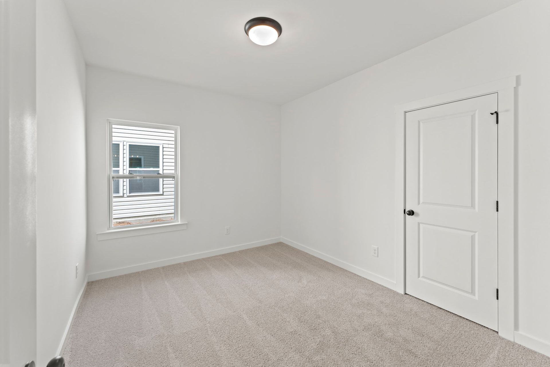 An empty bedroom with a window and a ceiling light.