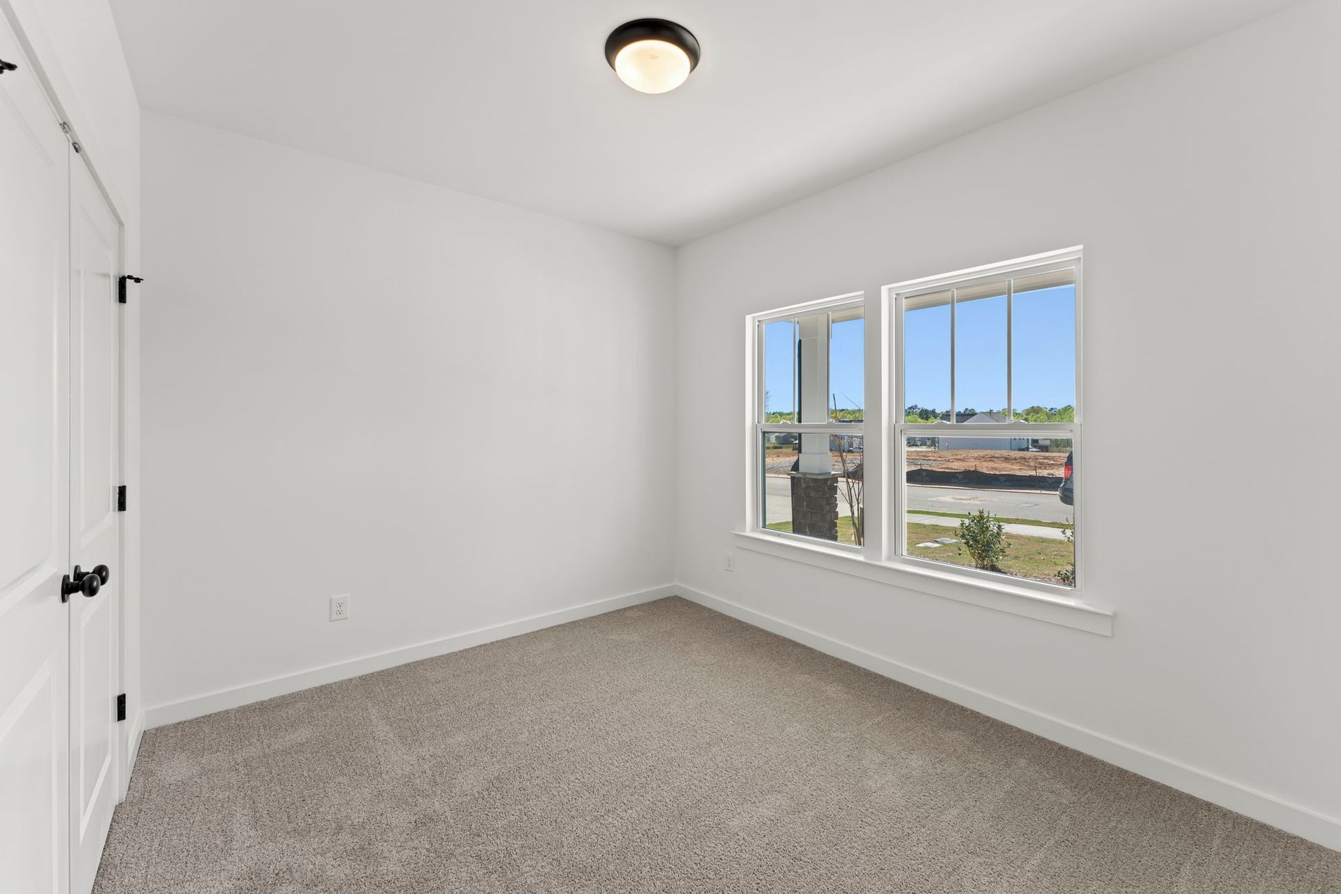 An empty bedroom with two windows and a ceiling light.