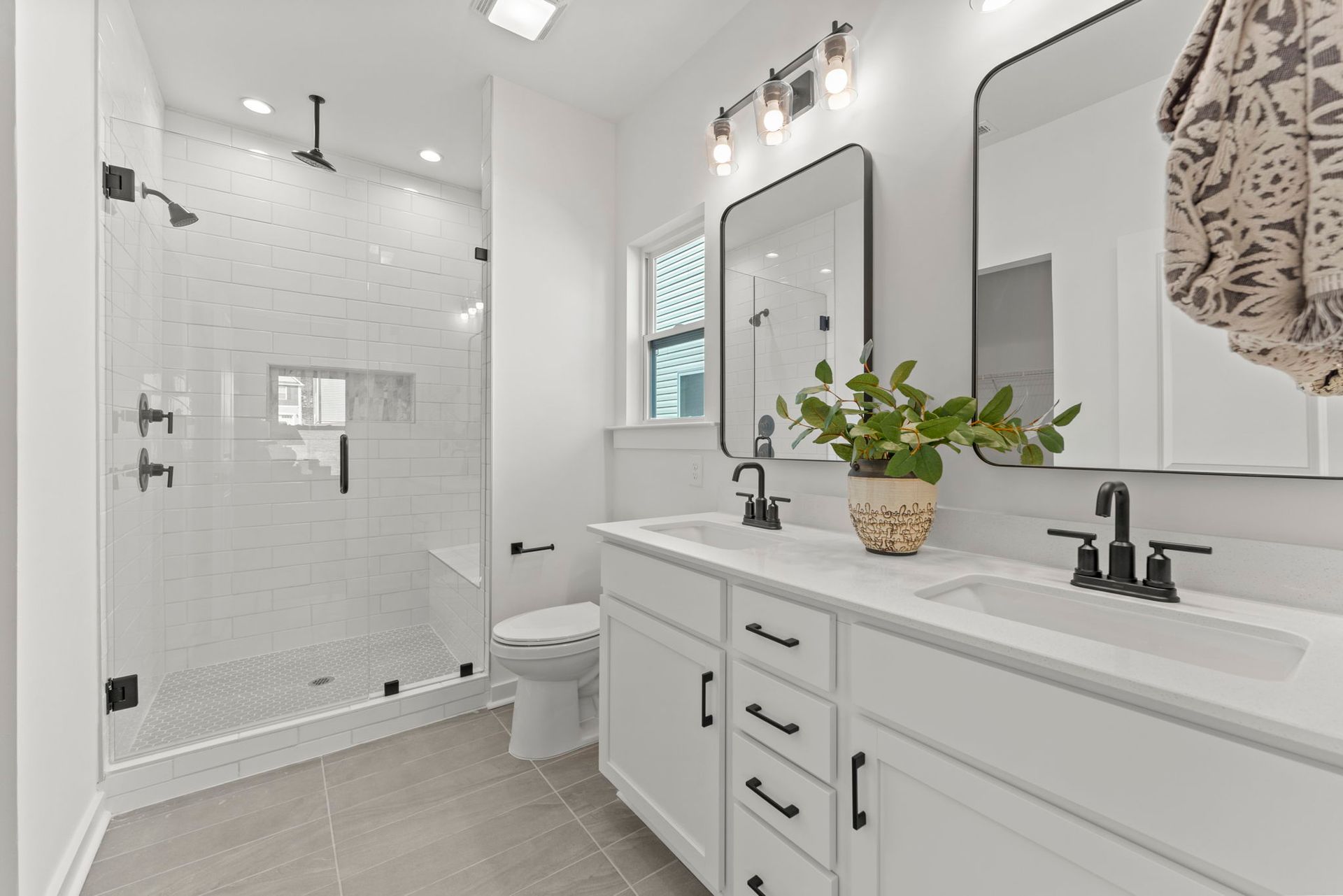 A bathroom with two sinks , a toilet , and a walk in shower.