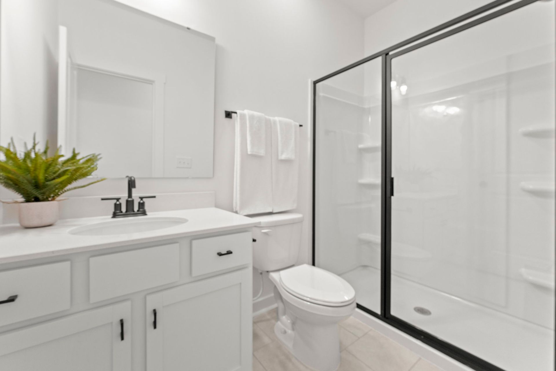 A bathroom with a toilet , sink , mirror and shower.