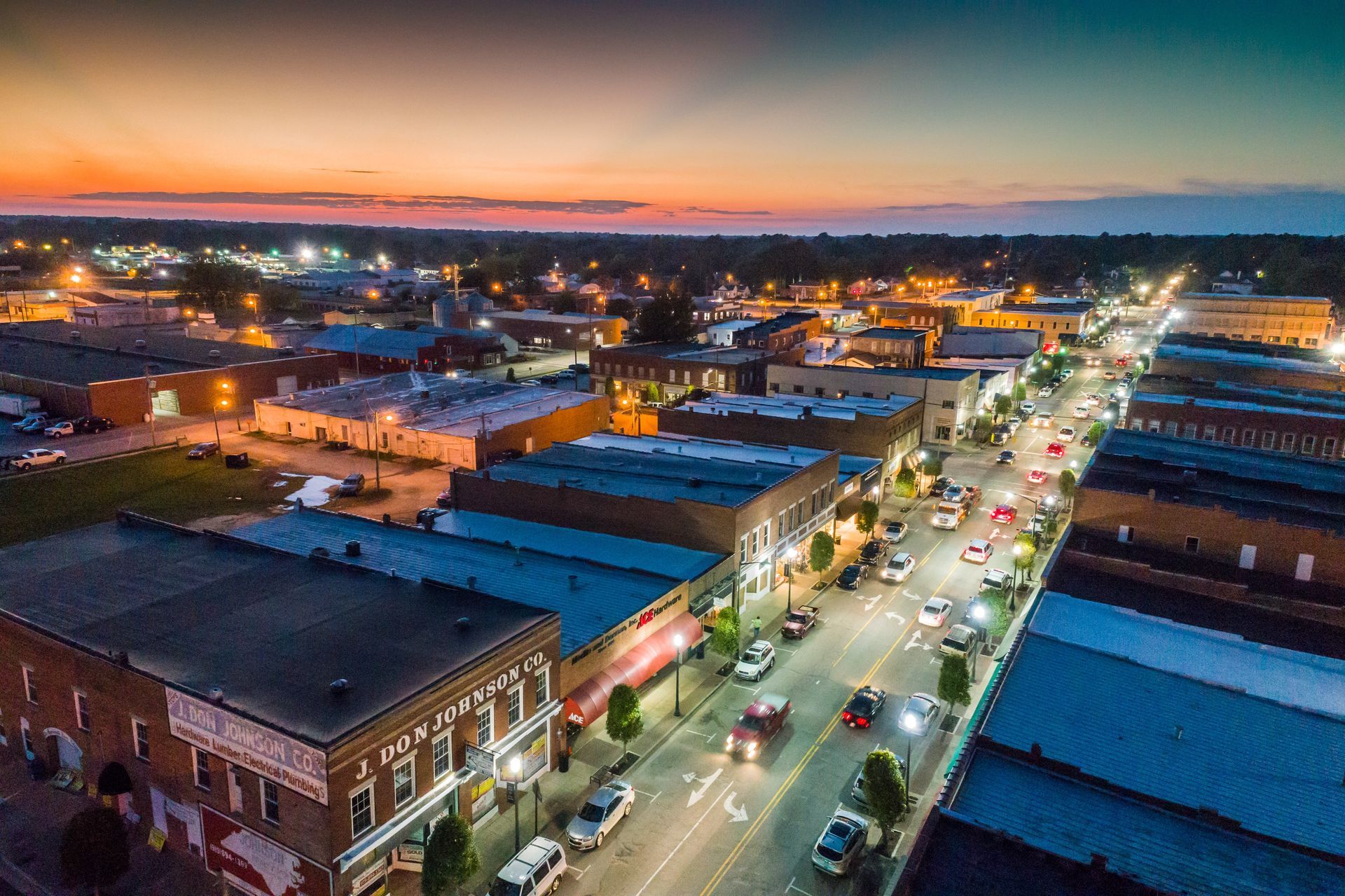 an aerial view of a small town with a sunset in the background