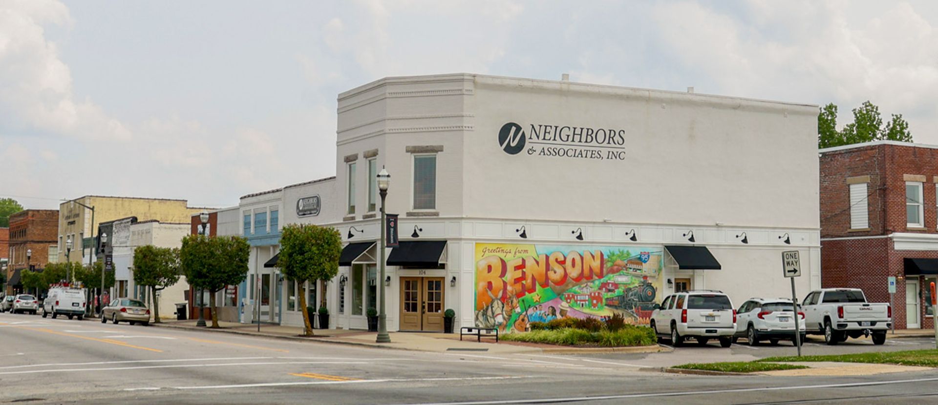 A white building with a mural on the side of it in a small town.