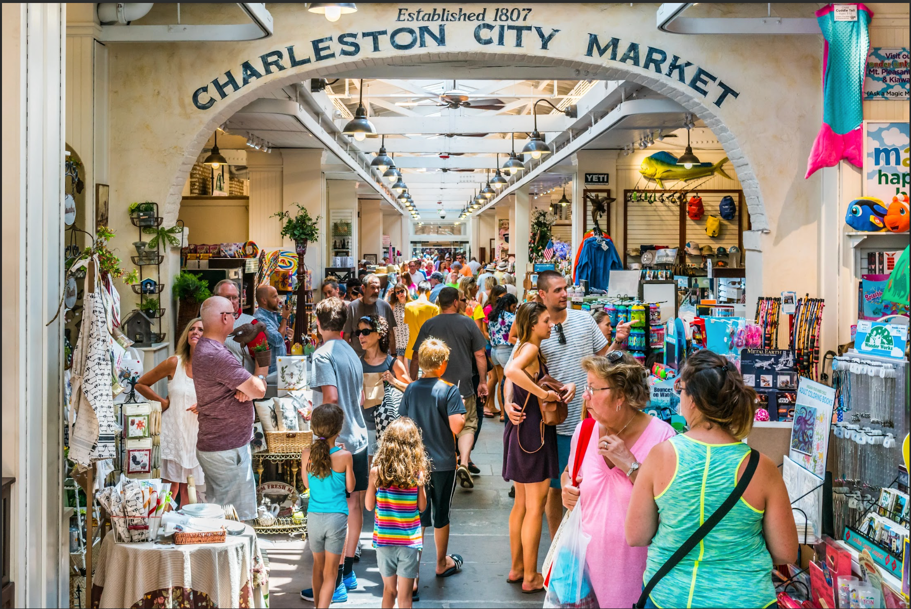 A crowd of people are shopping at the charleston city market.