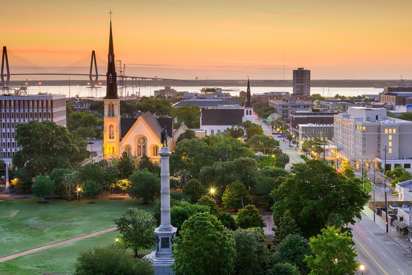 An aerial view of a city with a church and a statue in the foreground.