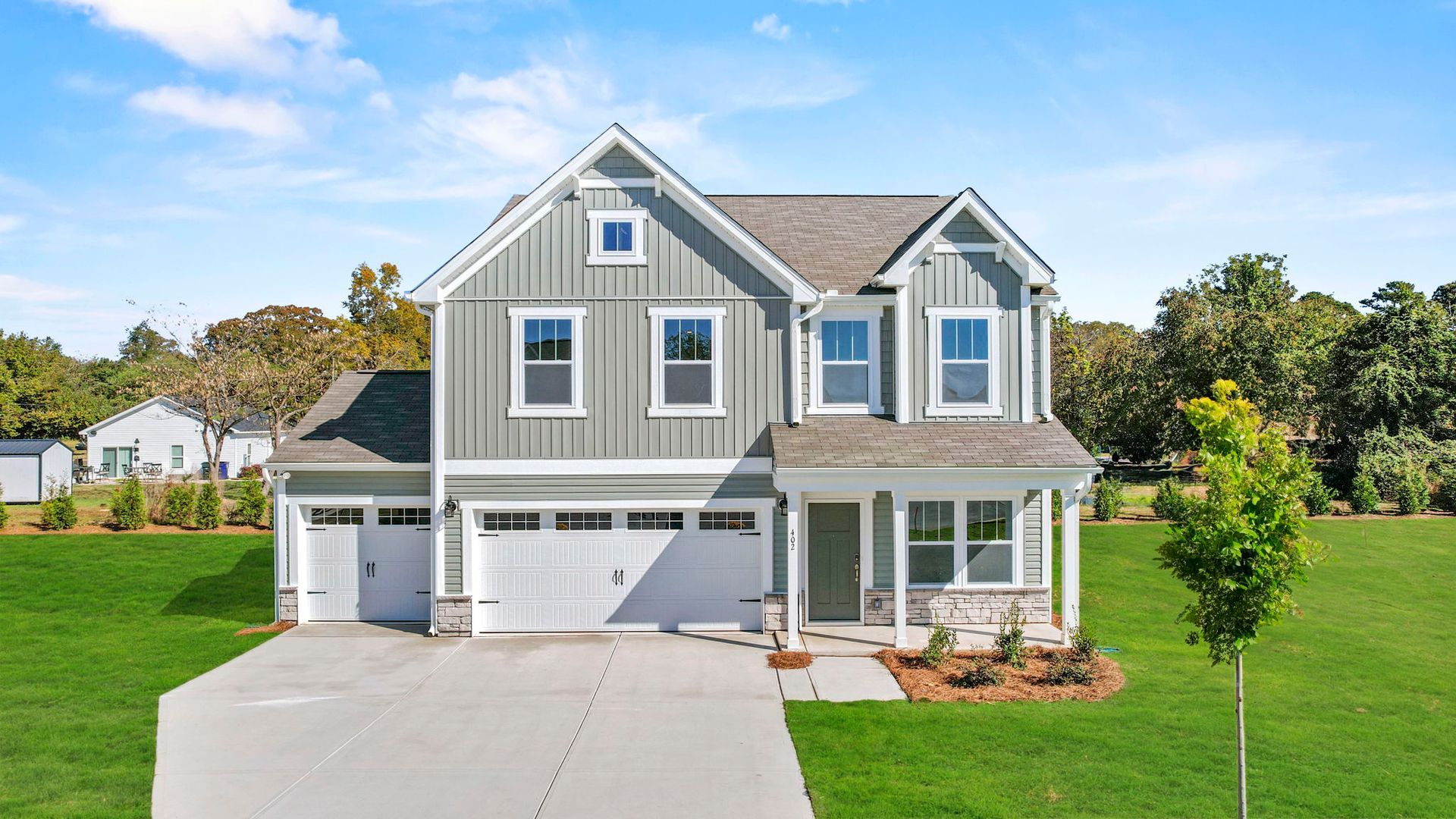 An aerial view of a large gray and white house with a large driveway.