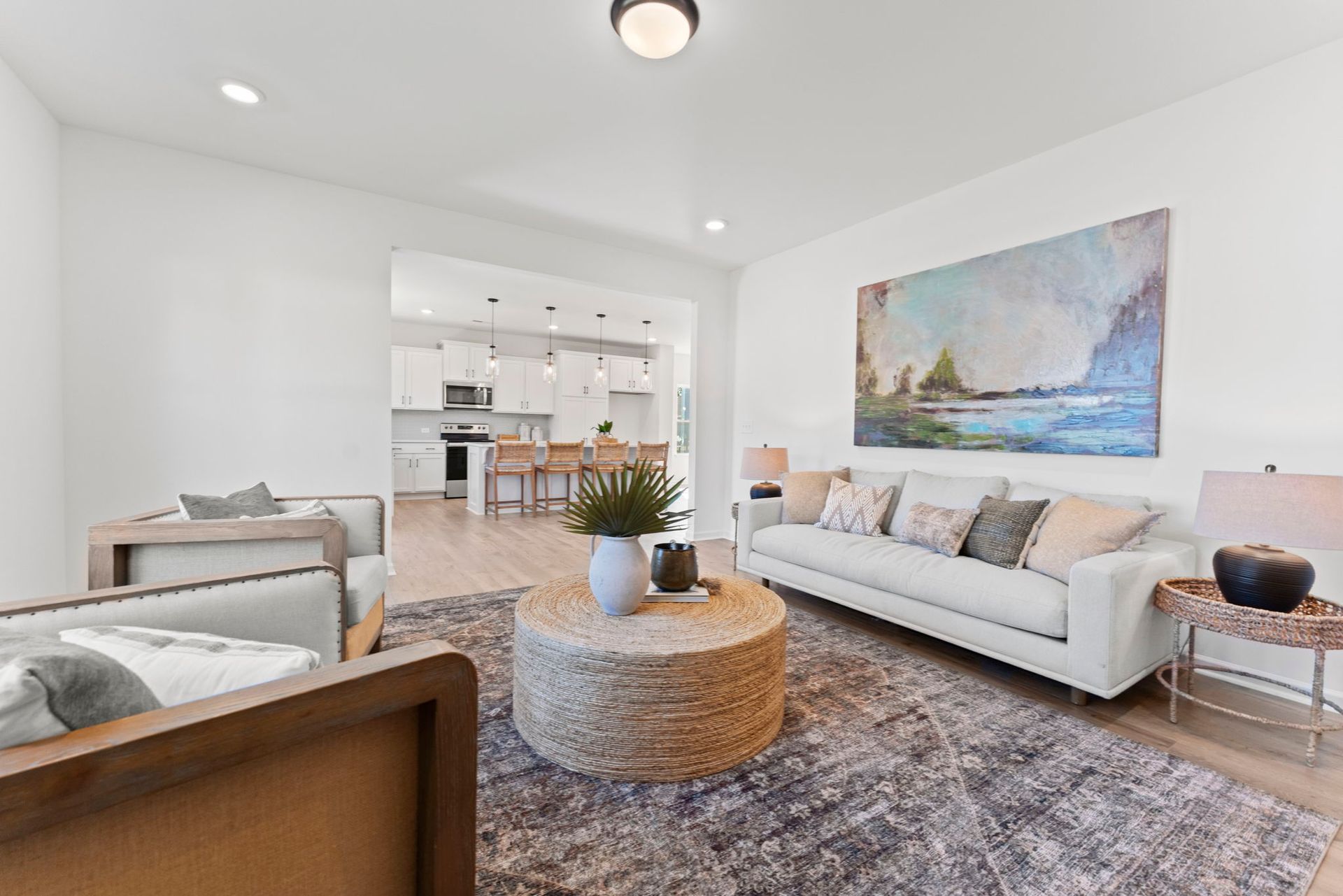 A living room with a couch , chairs , coffee table and a painting on the wall.
