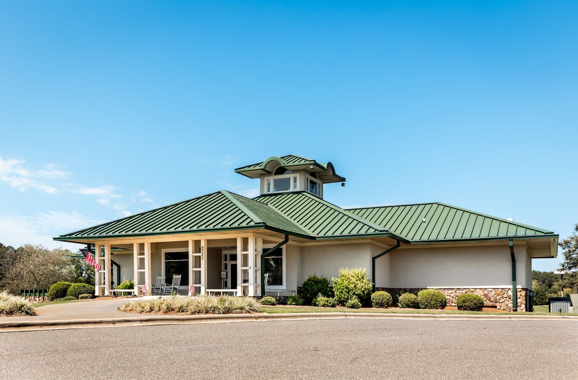 A white house with a green roof and a porch