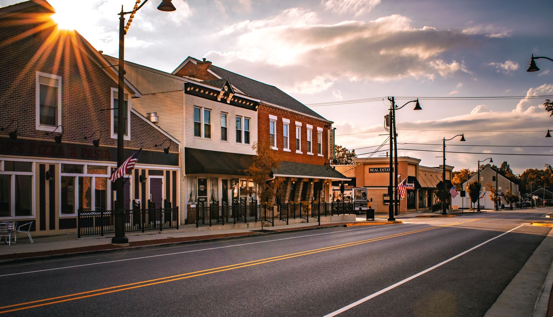 The sun is shining through the clouds on a small town street.