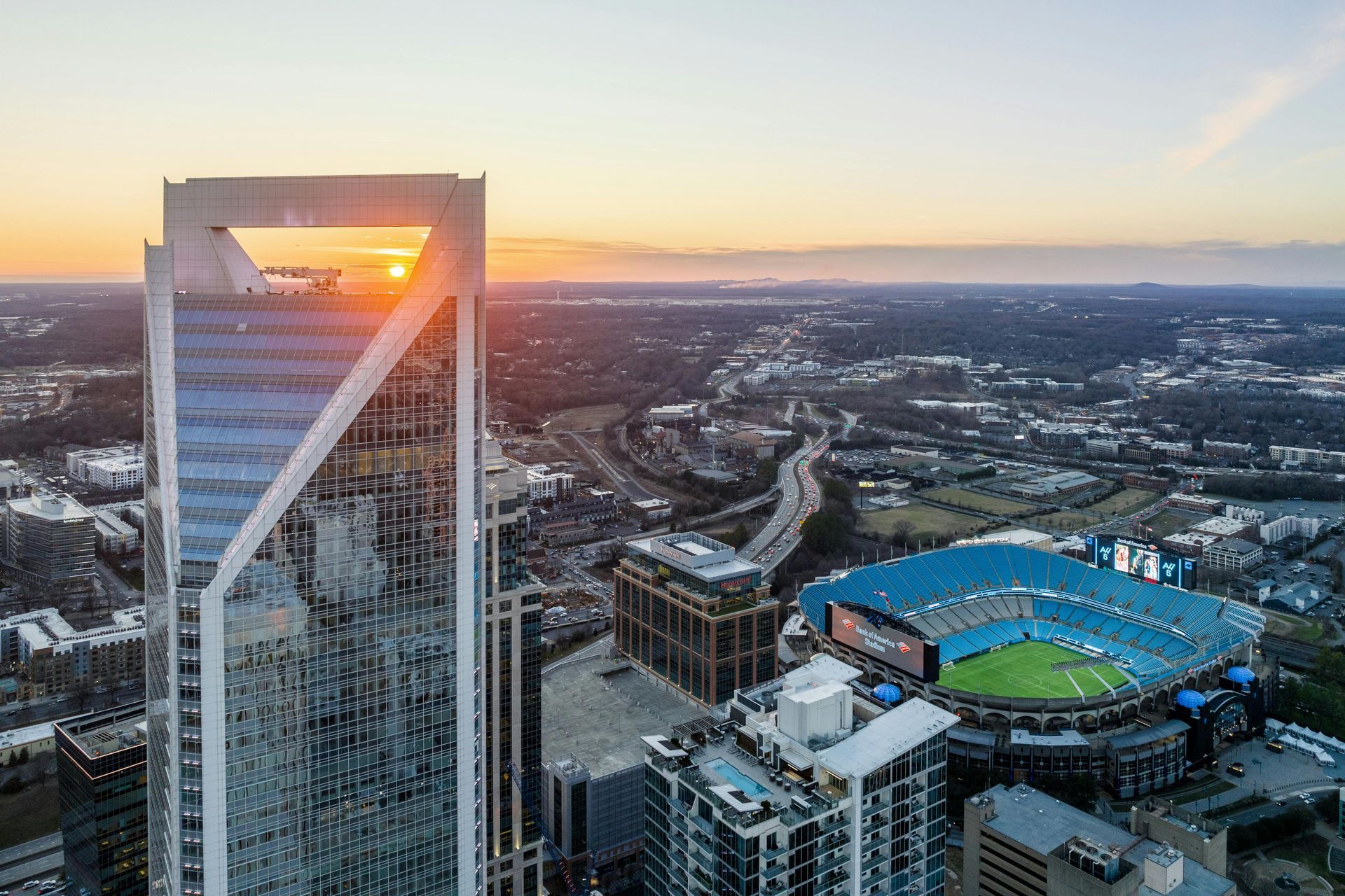 An aerial view of a city with a skyscraper in the foreground and a baseball stadium in the background.
