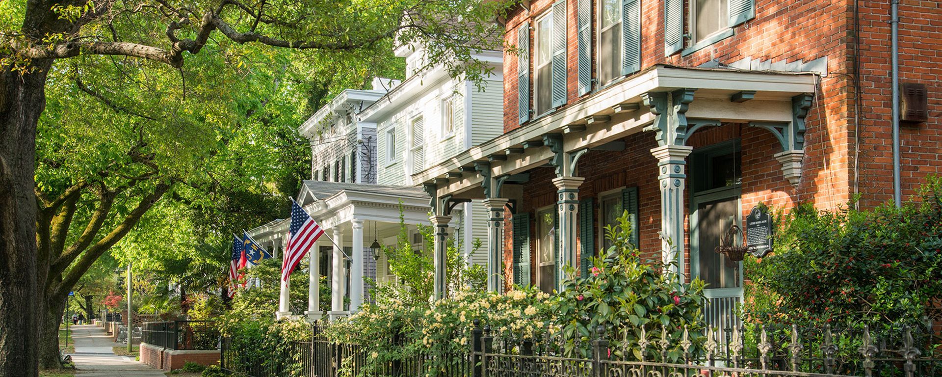 A row of houses with porches and american flags on them.