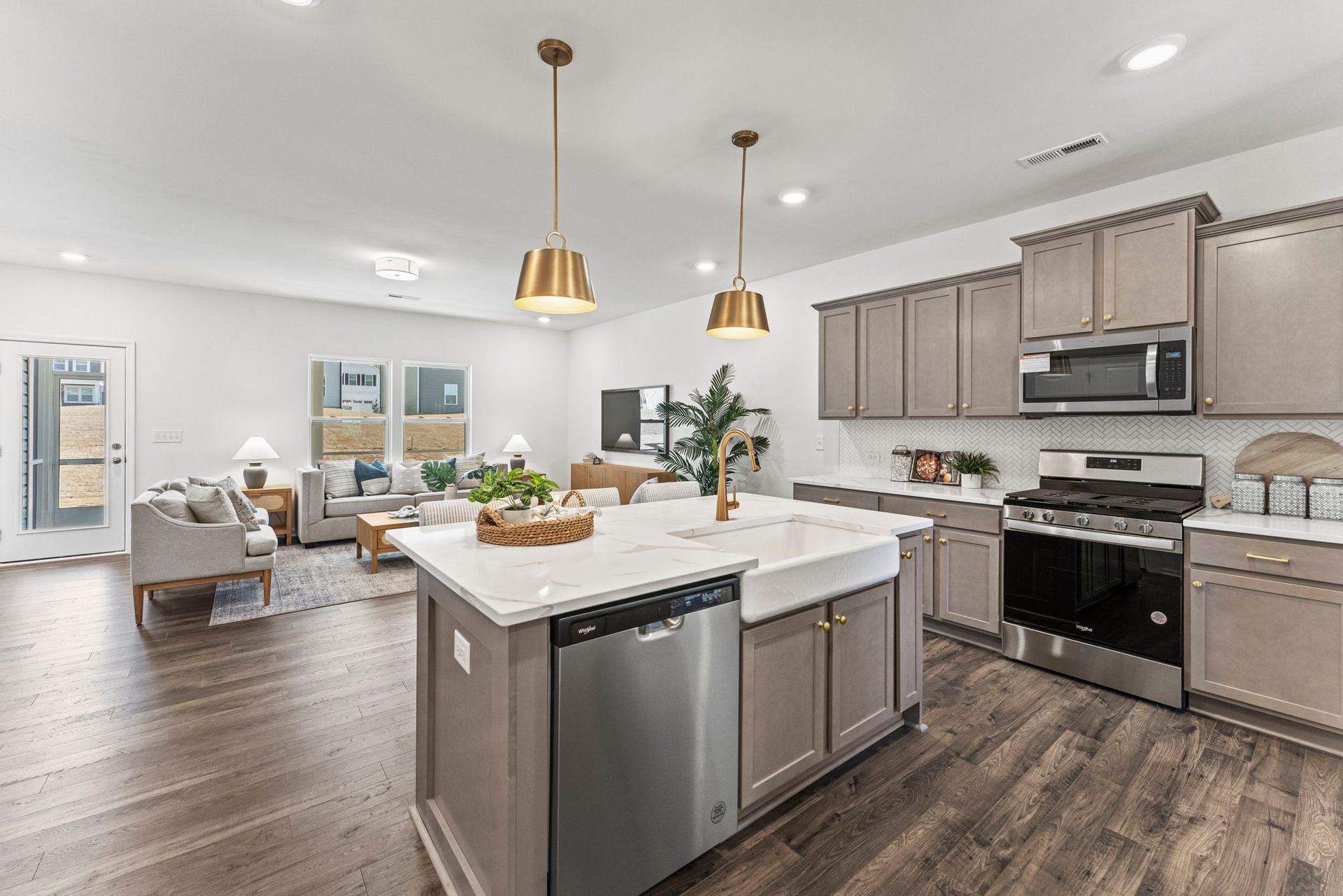 a kitchen in a model home with stainless steel appliances and a large island .