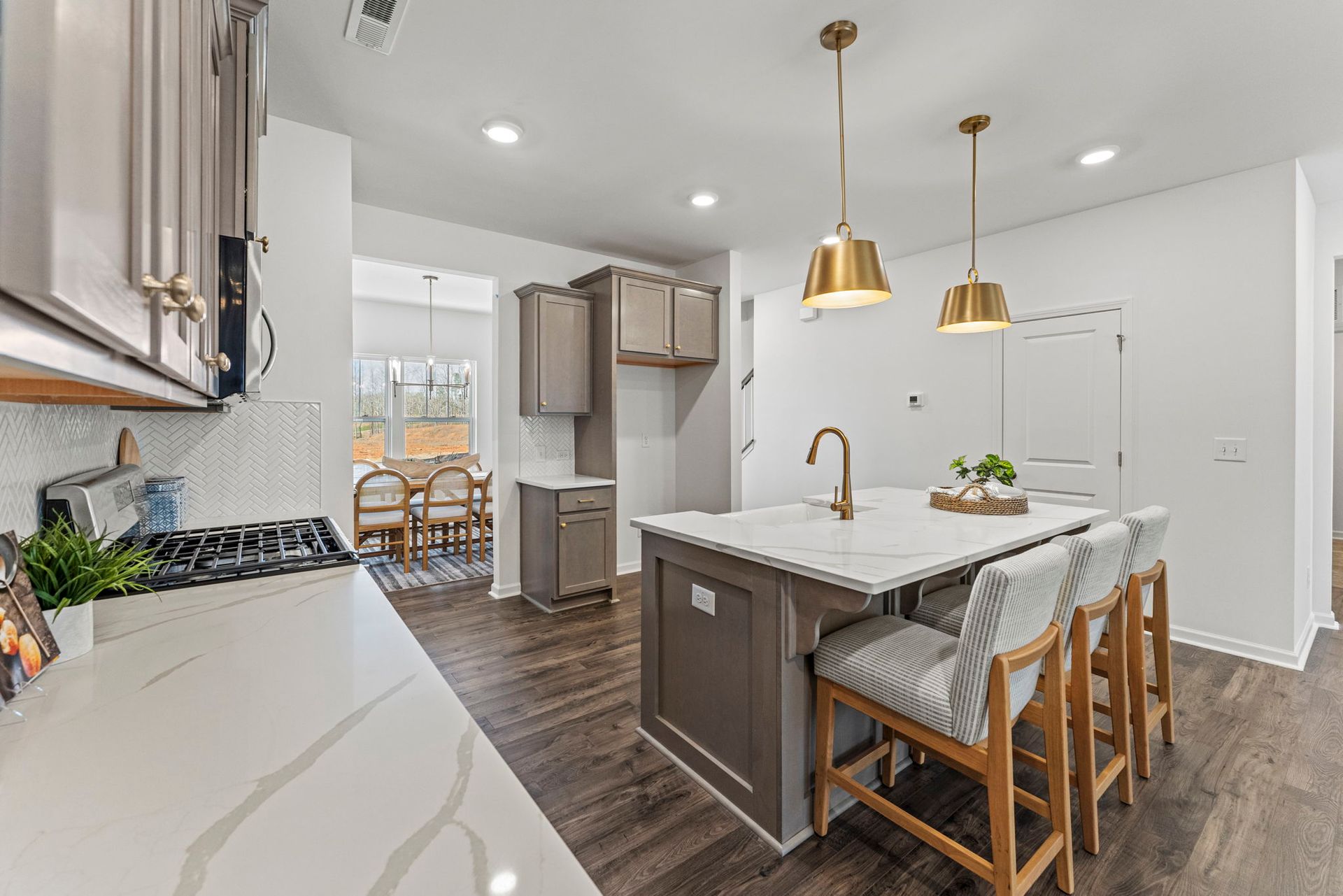 A kitchen with a large island , stools , and a stove.