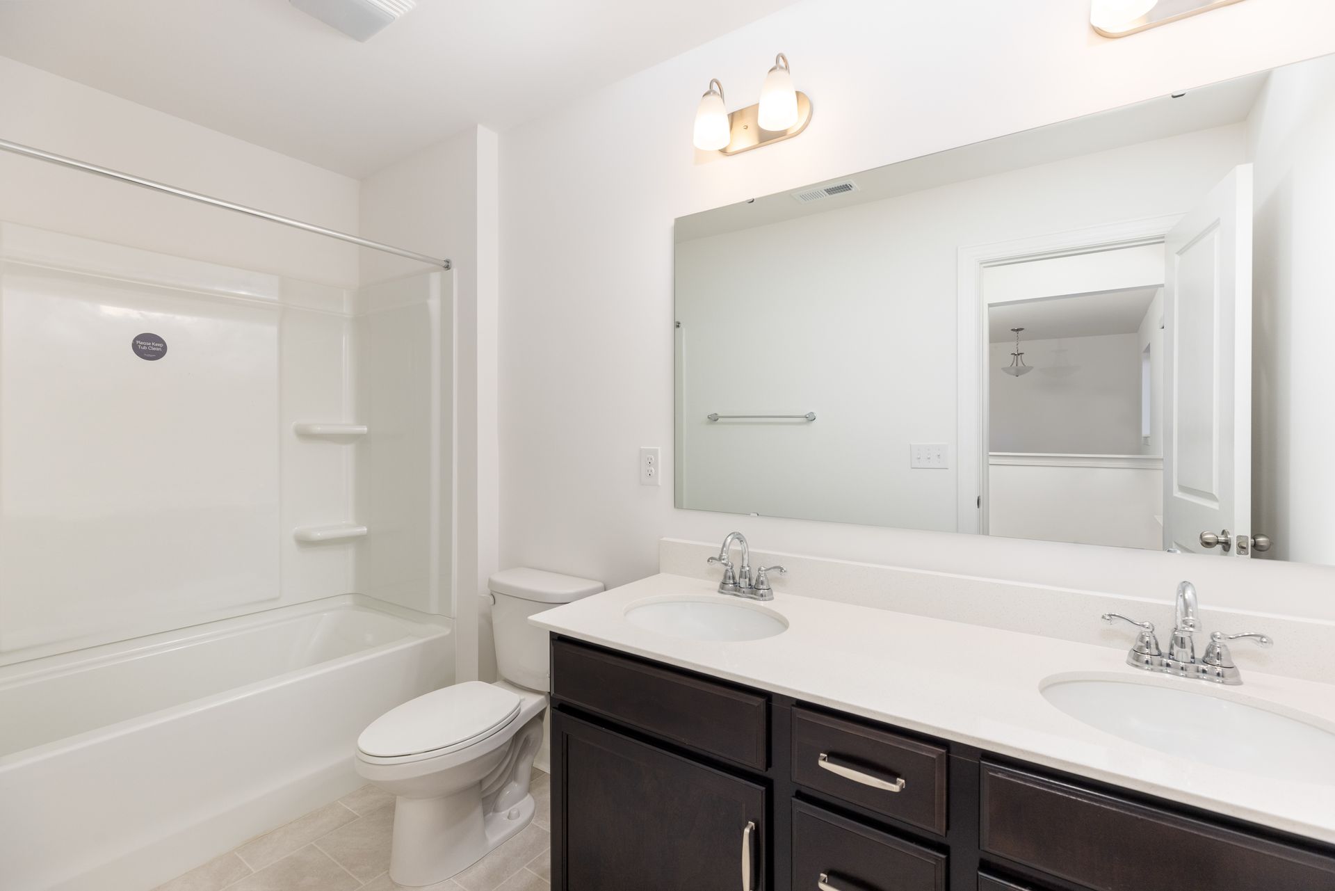 A bathroom with a toilet , sink , tub and mirror.