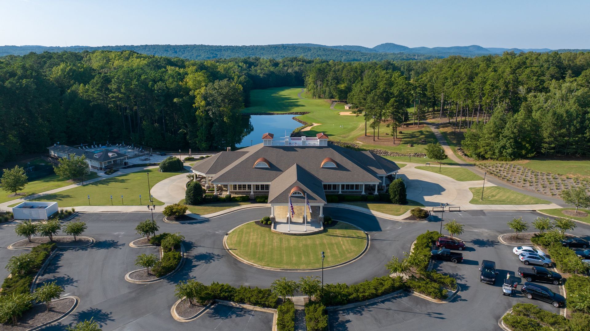 An aerial view of a golf course with a large building in the middle of it surrounded by trees.