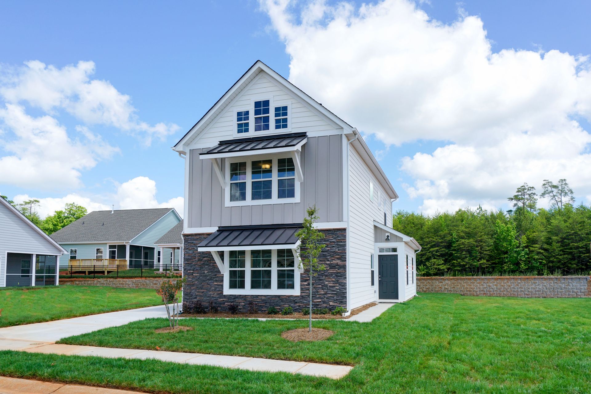 A house with a lot of windows is sitting on top of a lush green lawn.