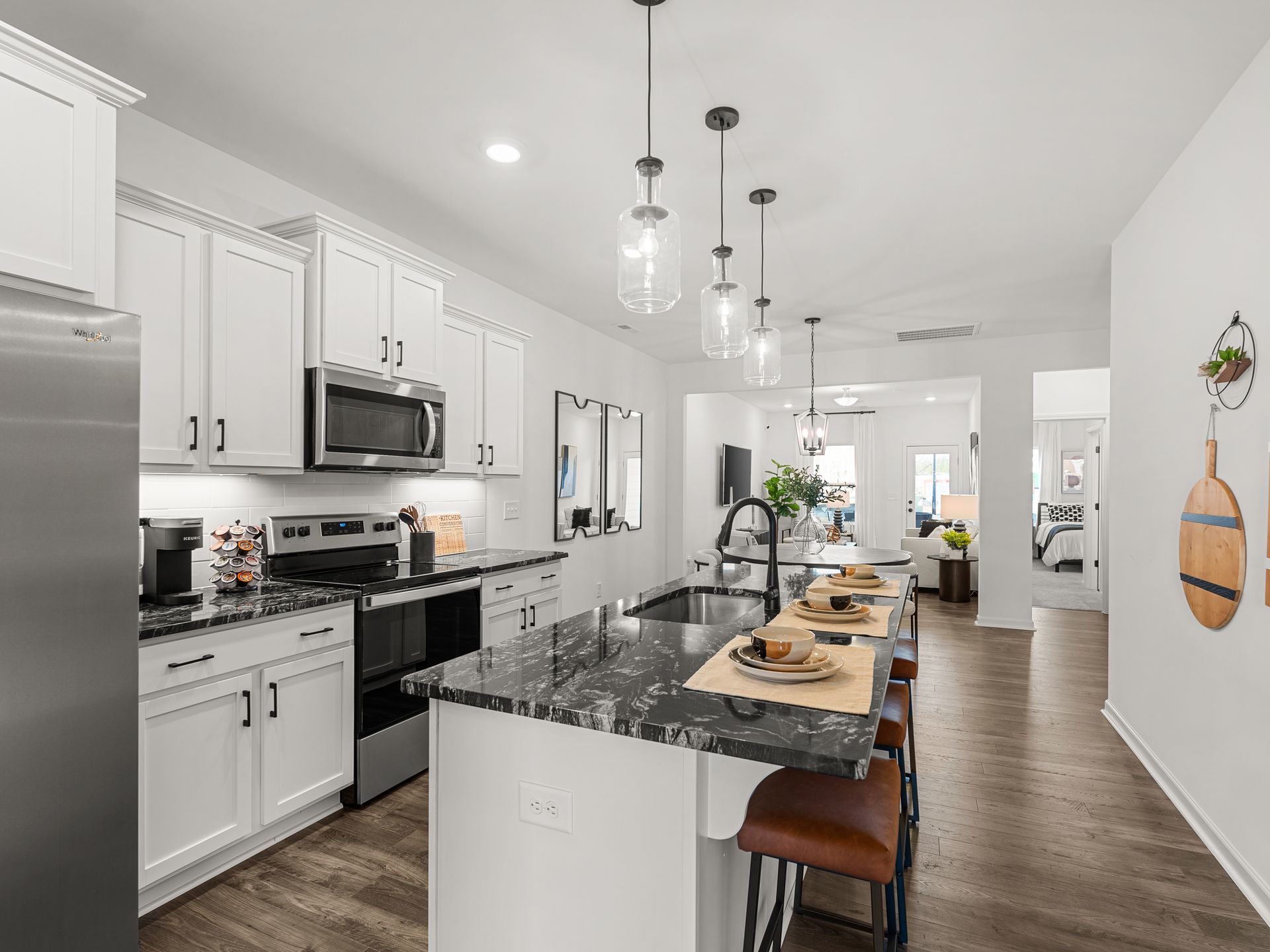 a kitchen with white cabinets , stainless steel appliances , granite counter tops and a large island .