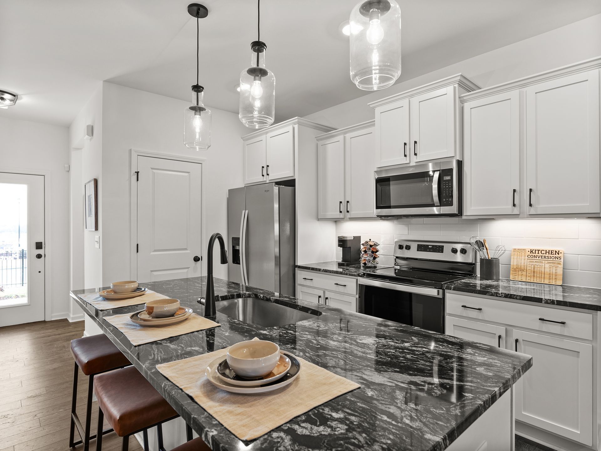A kitchen with white cabinets , granite counter tops , stainless steel appliances and a large island.