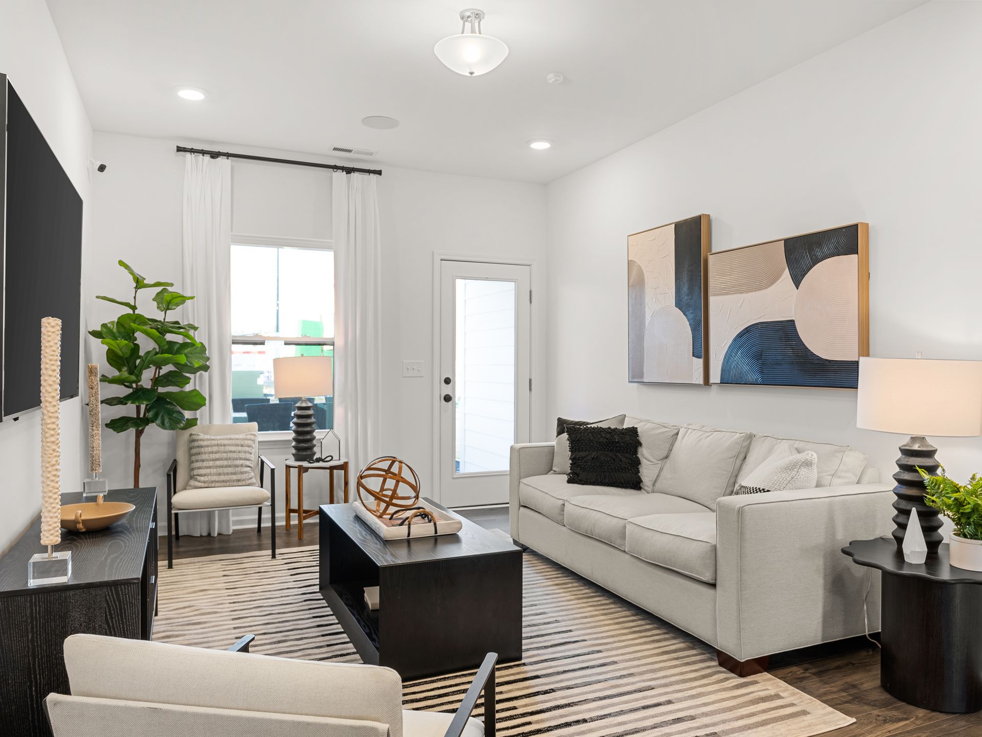 A living room with a couch , chairs , coffee table and television.
